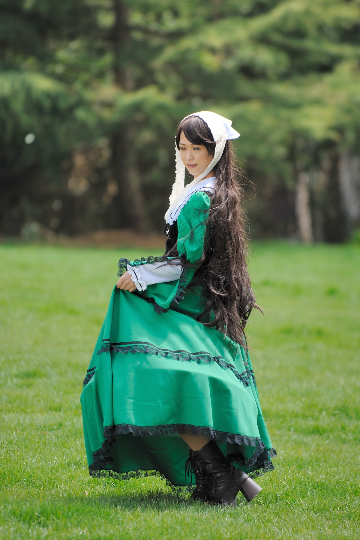 1girl black_footwear blurry blurry_background boots brown_hair depth_of_field dress full_body green_dress long_hair long_sleeves outdoors skirt_hold smile solo standing suiseiseki very_long_hair