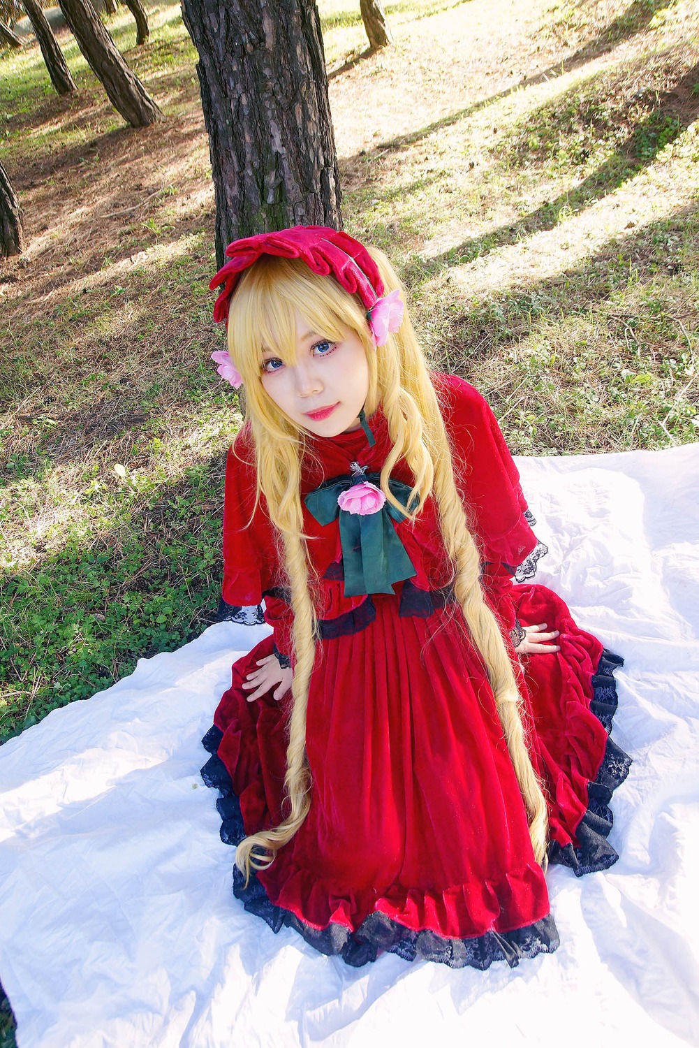 1girl blonde_hair blue_eyes bonnet brooch capelet dress flower lips long_hair long_sleeves looking_at_viewer outdoors red_dress shinku sitting solo