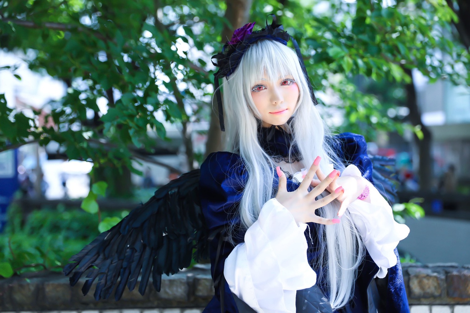 1girl 3d bangs black_wings blurry blurry_background blurry_foreground depth_of_field dress feathered_wings flower long_hair long_sleeves looking_at_viewer nail_polish outdoors red_eyes smile solo suigintou white_hair wings