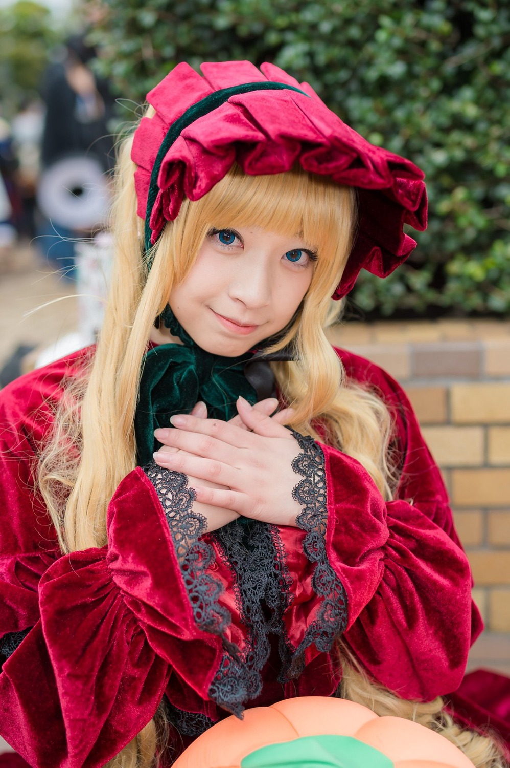 1girl bangs blonde_hair blue_eyes blunt_bangs blurry blurry_background blurry_foreground bonnet bow depth_of_field dress lips long_hair looking_at_viewer photo realistic shinku sitting smile solo