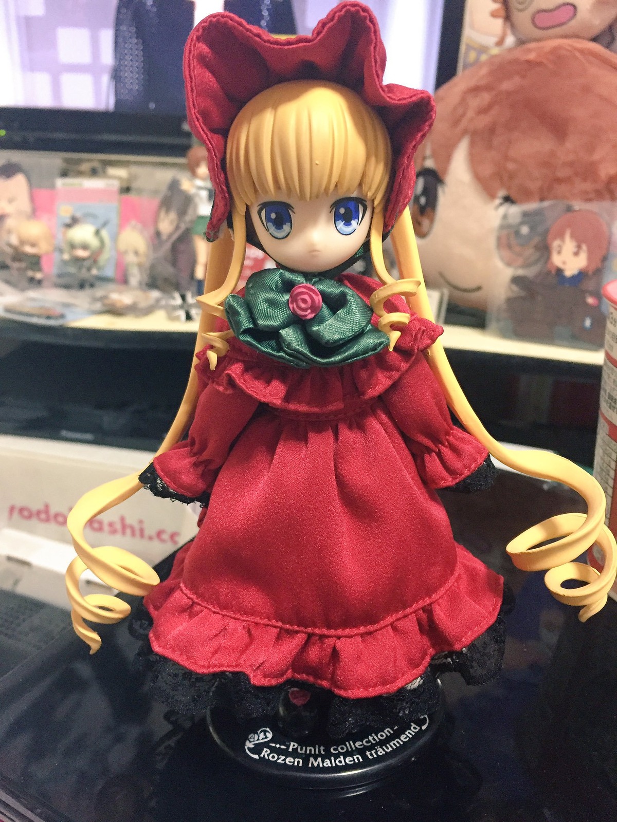 1girl blonde_hair blue_eyes blurry bonnet bow depth_of_field doll dress drill_hair figure flower long_hair long_sleeves looking_at_viewer photo red_dress reflection rose shinku solo standing very_long_hair