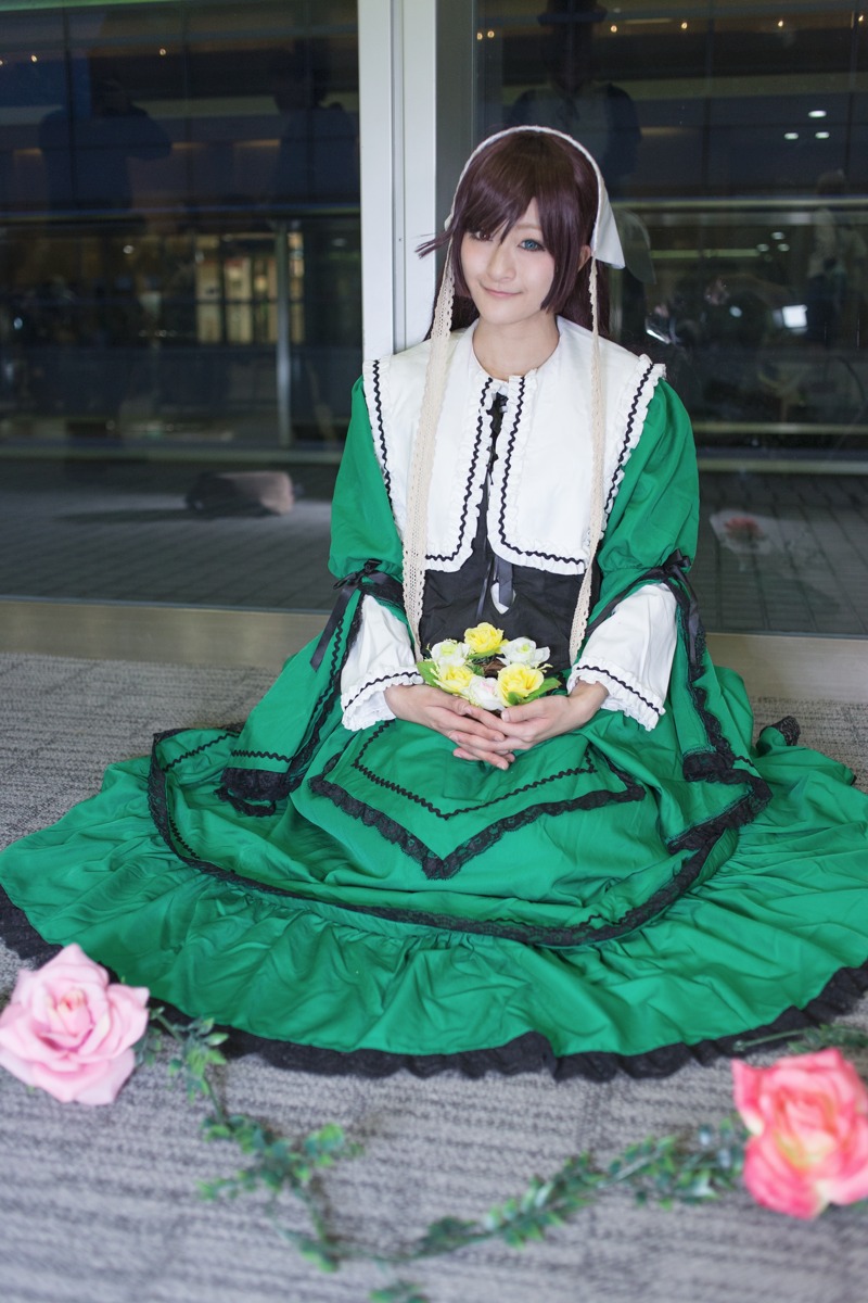 1girl blue_eyes blurry brown_hair dress flower green_dress long_sleeves looking_at_viewer pink_rose rose sitting smile solo suiseiseki