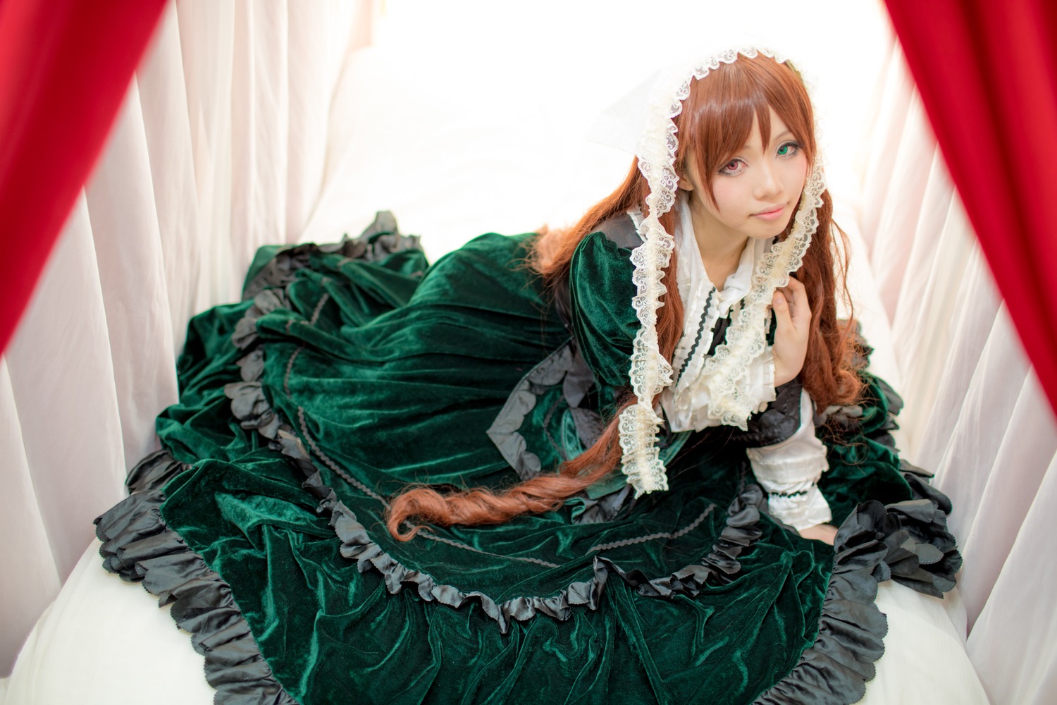 1girl brown_hair closed_mouth curtains dress frills green_dress green_eyes lips lolita_fashion long_hair long_sleeves looking_at_viewer sitting solo suiseiseki