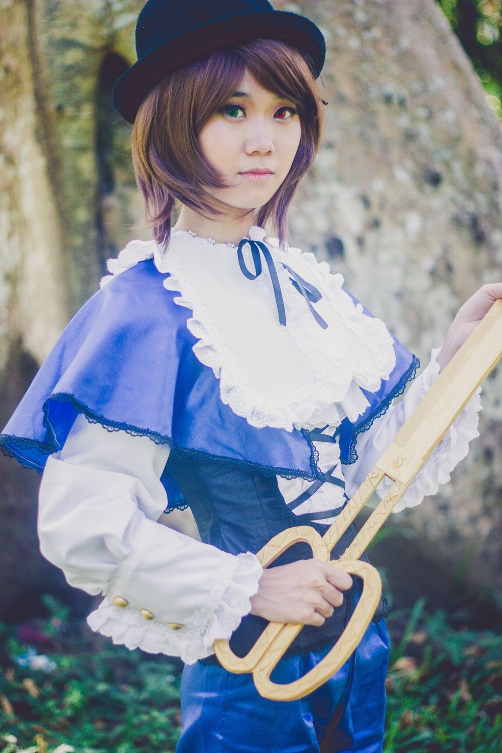 1girl blue_dress blue_ribbon blurry blurry_background brown_hair bush capelet depth_of_field dress frills hat heterochromia long_sleeves outdoors ribbon short_hair solo souseiseki