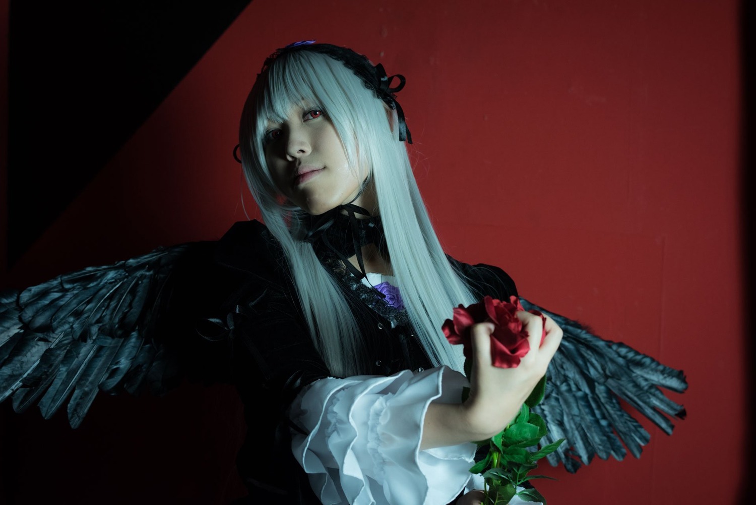 1girl angel_wings black_wings dress feathered_wings feathers flower frills hairband long_hair long_sleeves looking_at_viewer red_background red_eyes simple_background solo solo_wing suigintou upper_body white_wings wings