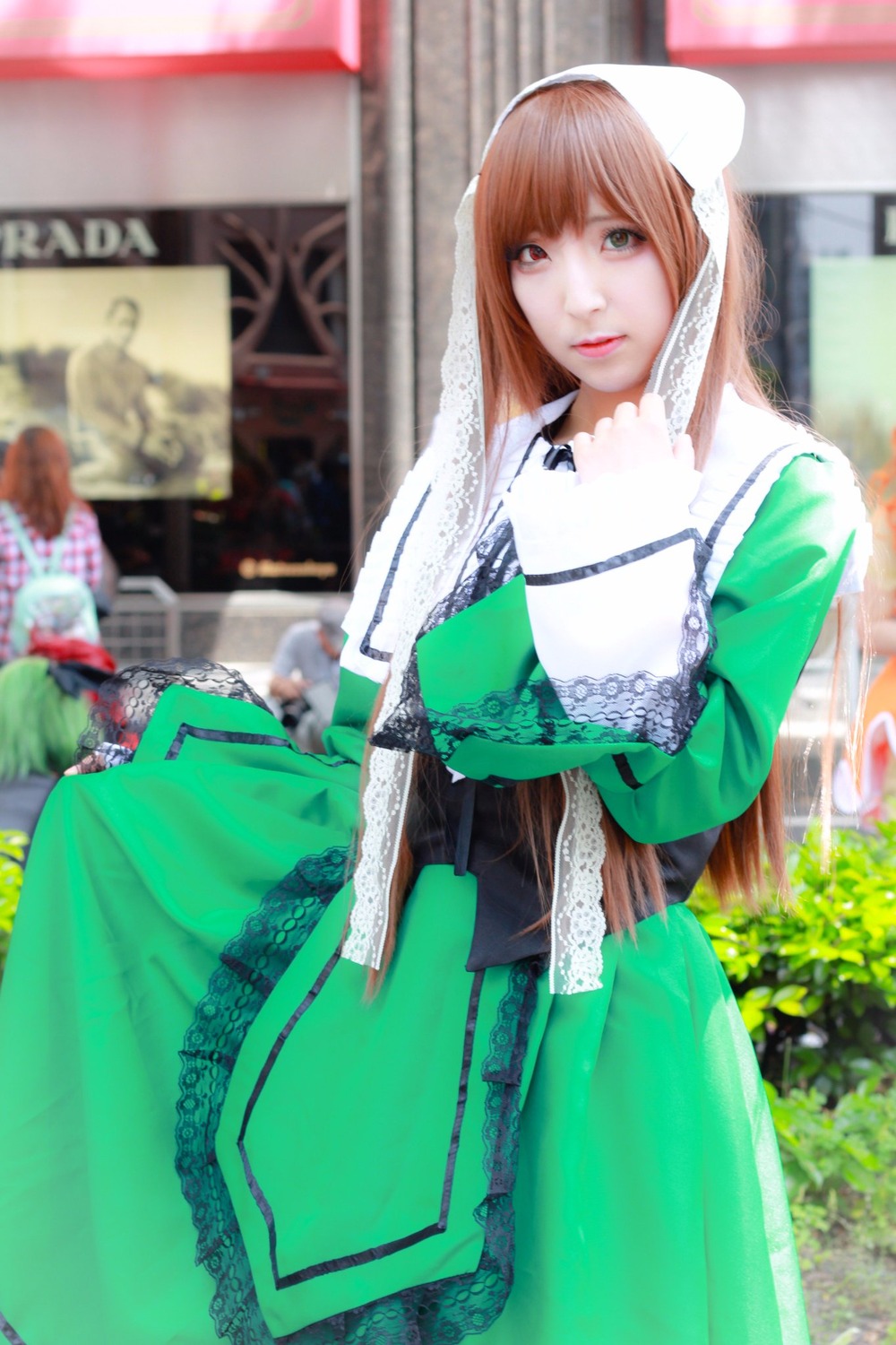 1girl 3d bangs blurry blurry_background blurry_foreground brown_hair depth_of_field dress green_dress green_eyes lips long_hair looking_at_viewer photo solo suiseiseki