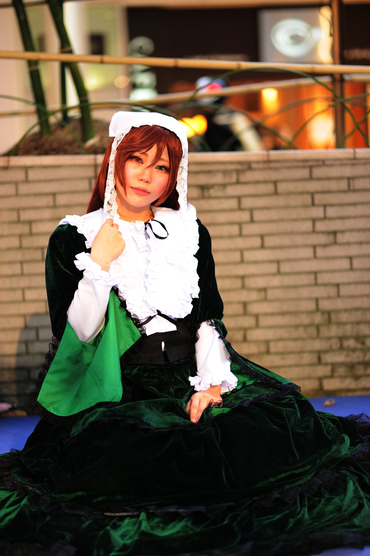 1girl bangs blurry brown_hair depth_of_field dress green_dress long_sleeves looking_at_viewer sitting solo suiseiseki