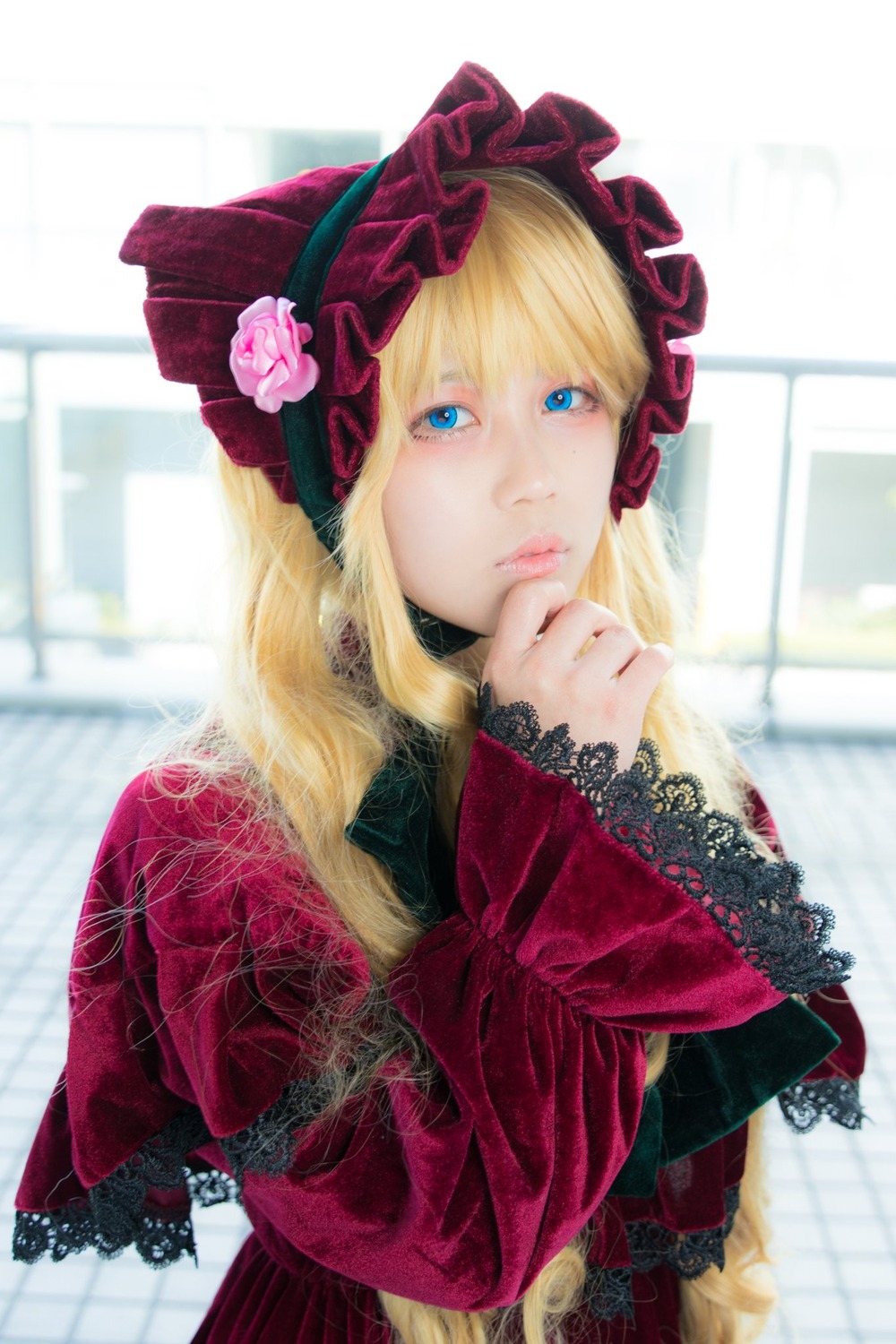 1girl bangs blonde_hair blue_eyes blurry blurry_background bonnet bow capelet depth_of_field dress flower lolita_fashion long_hair long_sleeves looking_at_viewer photo red_dress rose shinku solo