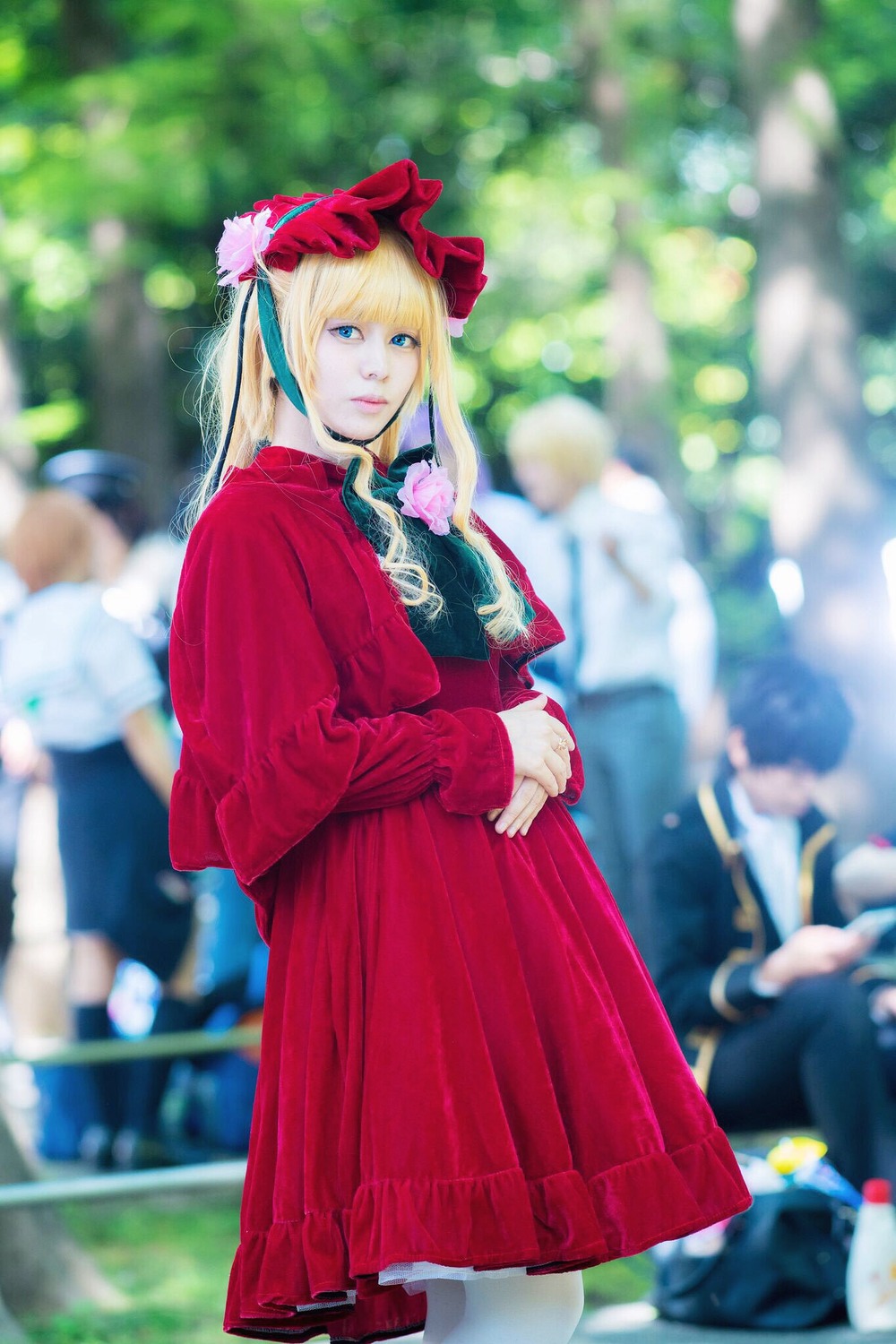 1girl blonde_hair blue_eyes blurry blurry_background blurry_foreground depth_of_field dress long_hair looking_at_viewer outdoors red_dress shinku solo solo_focus standing