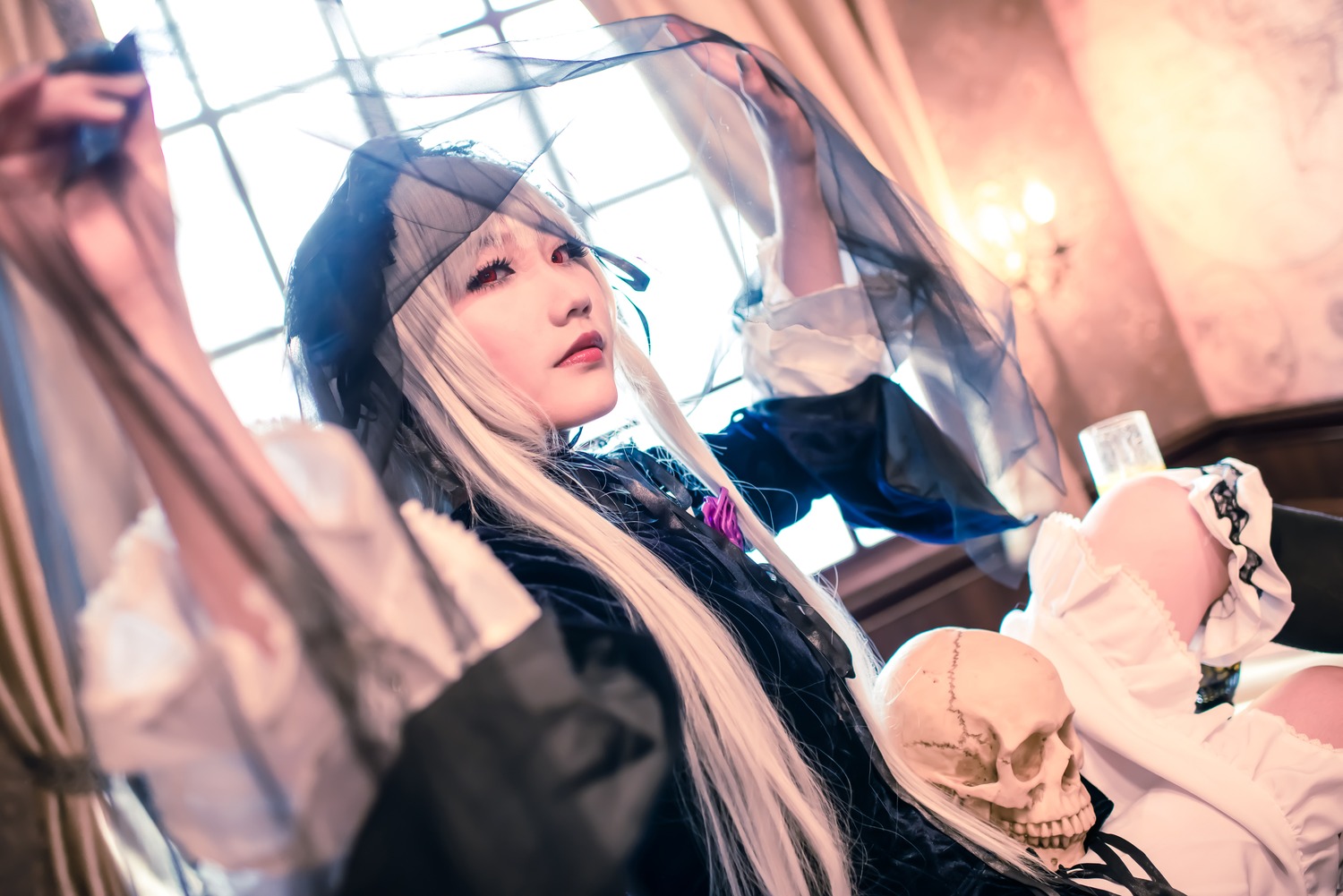 1girl blonde_hair blurry blurry_background blurry_foreground depth_of_field dress holding indoors jewelry lips long_hair sitting solo suigintou