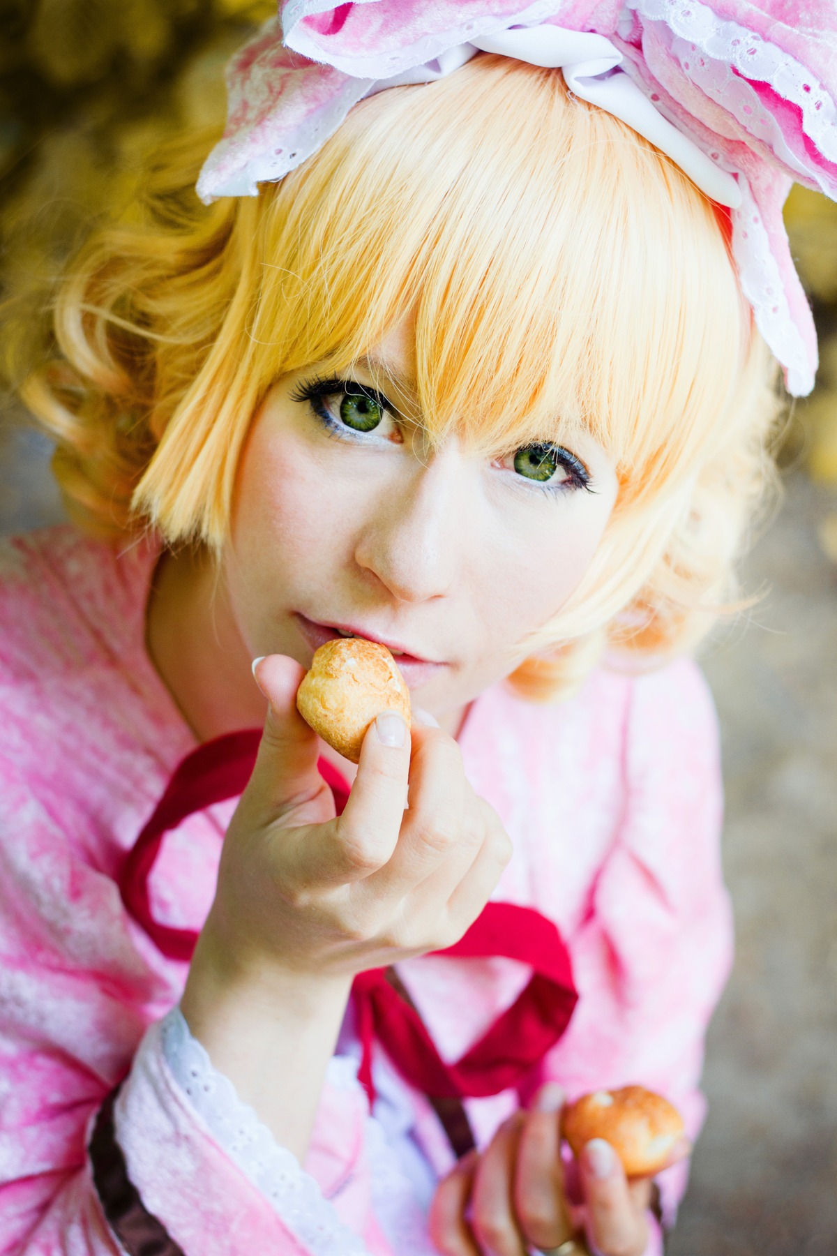 1girl blonde_hair blurry blurry_background blurry_foreground bow depth_of_field dress eating food frills green_eyes hat hinaichigo holding_food lips looking_at_viewer photo realistic red_ribbon ribbon short_hair solo