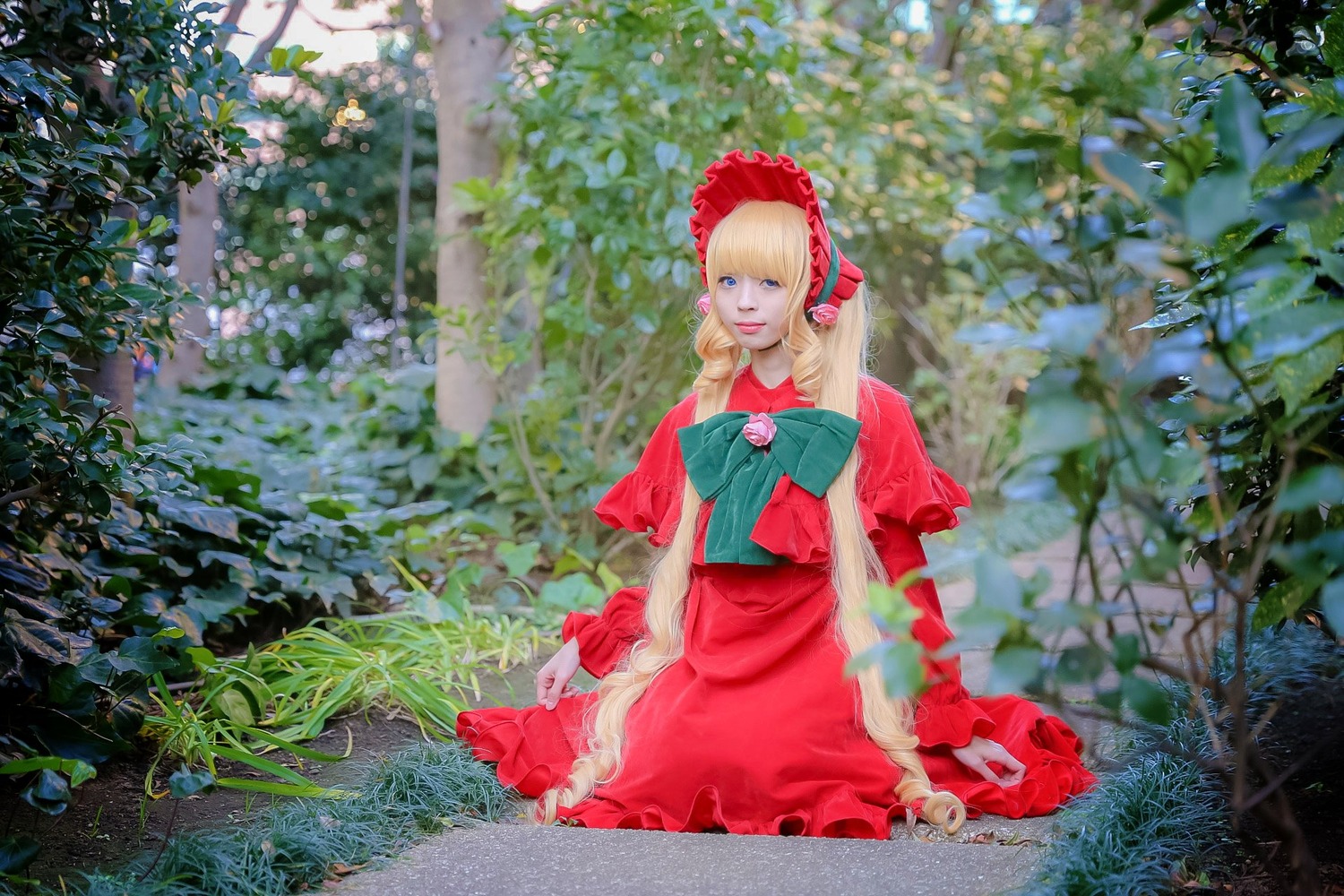 1girl blonde_hair blue_eyes blurry bonnet bow capelet depth_of_field dress flower frills long_hair plant red_dress shinku solo