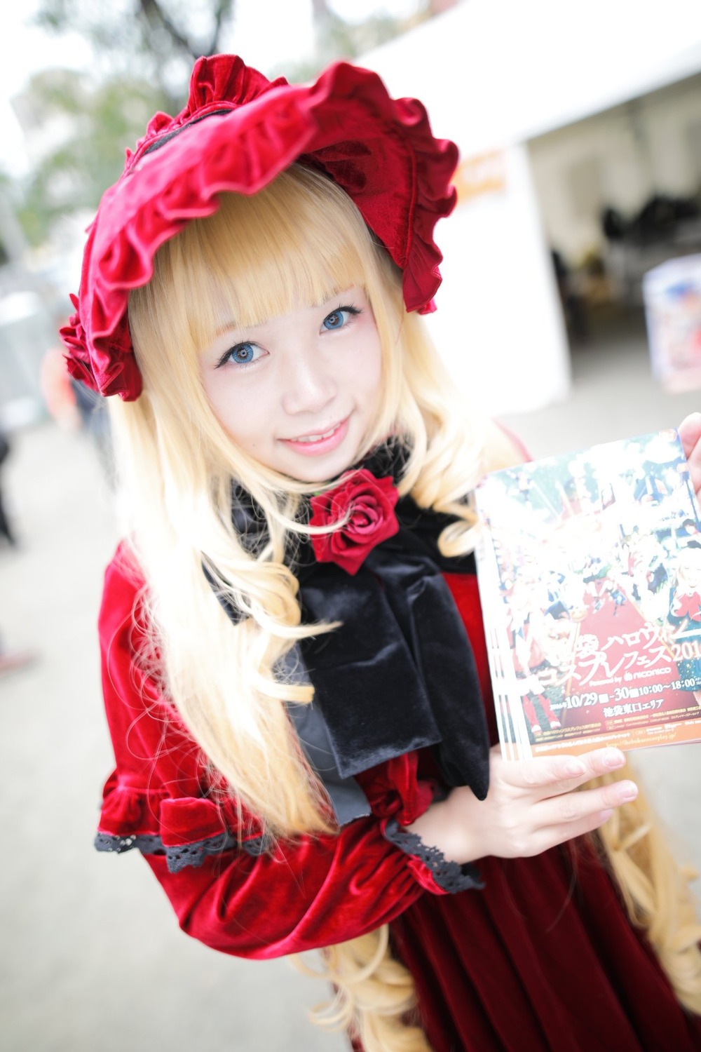 1girl bangs blonde_hair blue_eyes blurry blurry_background blurry_foreground depth_of_field dress flower lips long_hair looking_at_viewer photo realistic red_flower rose shinku smile solo