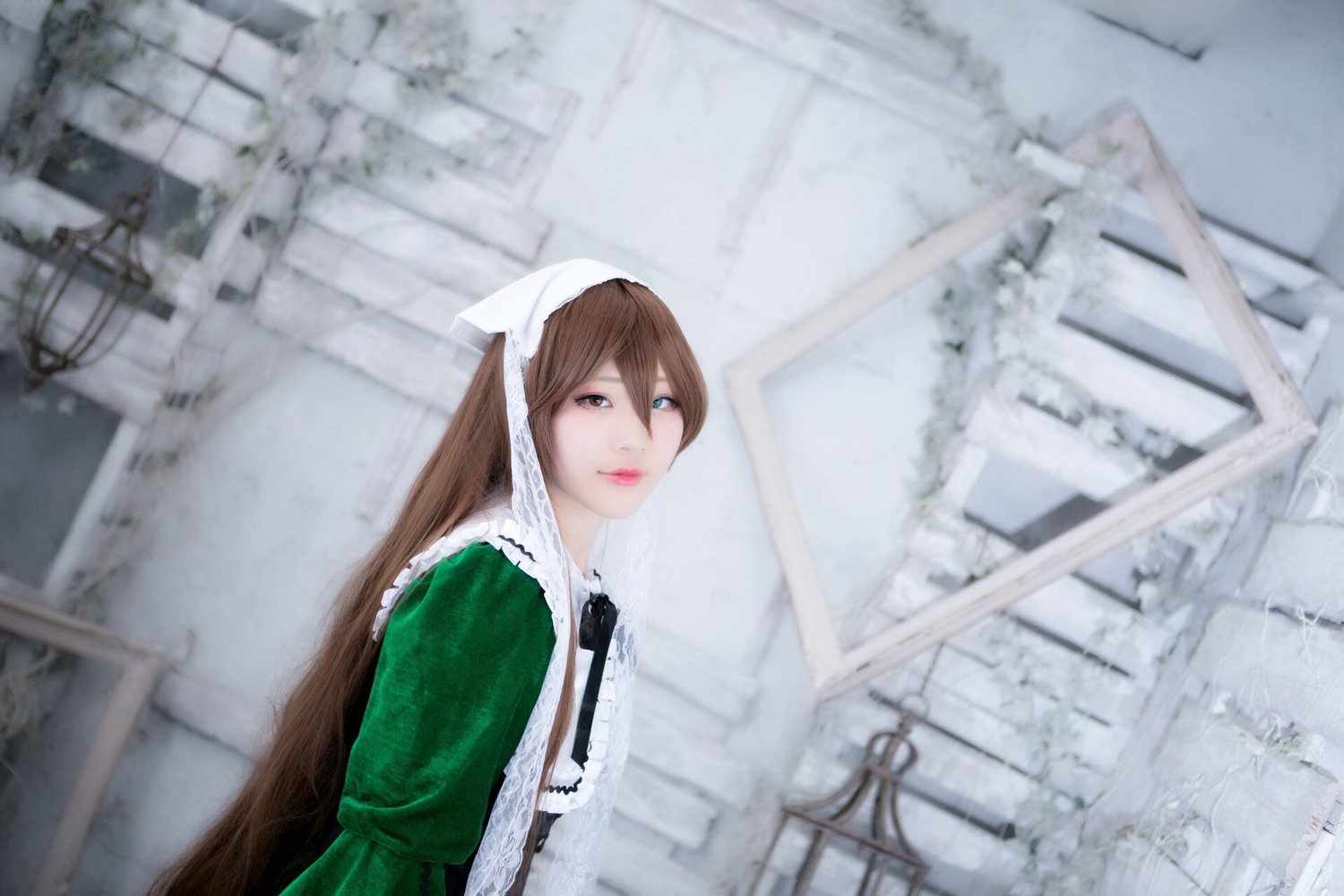 1girl apron blurry blurry_background brown_hair building depth_of_field dress green_dress lips long_hair looking_at_viewer outdoors solo suiseiseki upper_body white_apron