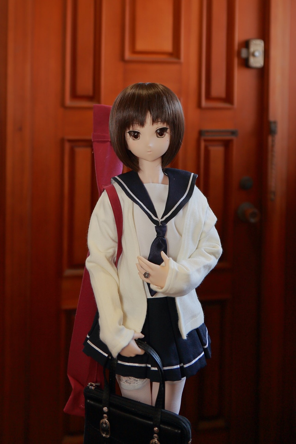 1girl bag bangs blurry brown_eyes brown_hair cowboy_shot doll human kashiwaba_tomoe long_sleeves looking_at_viewer pleated_skirt school_bag school_uniform serafuku short_hair skirt solo standing