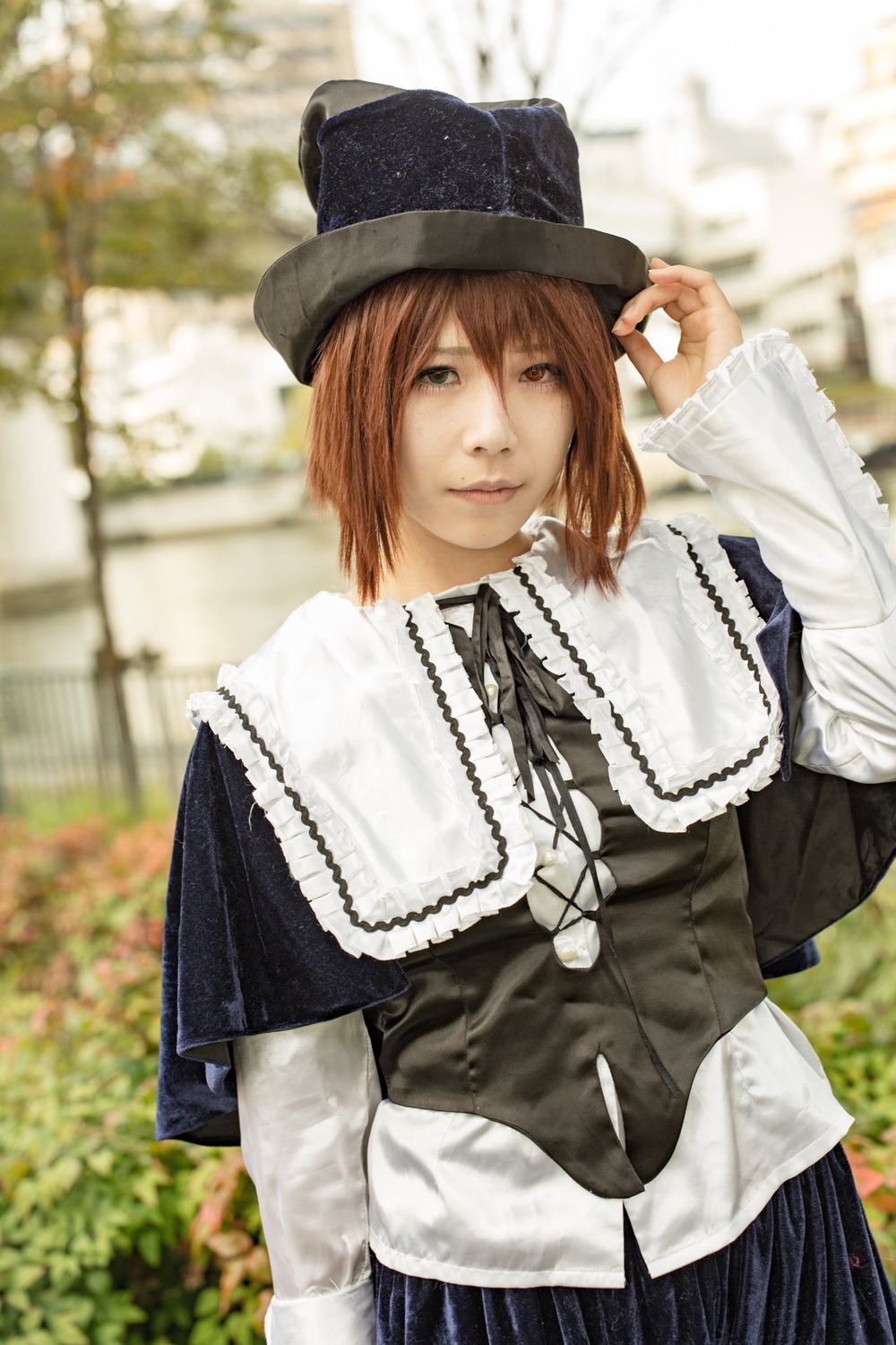 1girl 3d blurry blurry_background brown_eyes brown_hair capelet depth_of_field dress hat long_sleeves looking_at_viewer outdoors photo photo_background short_hair solo souseiseki