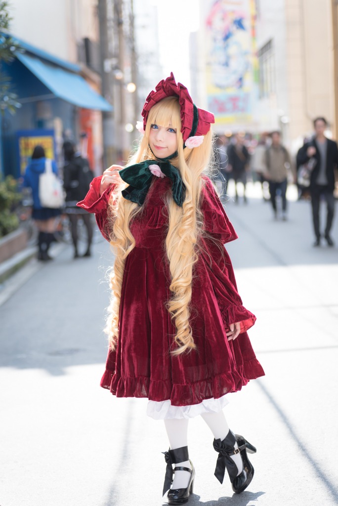 1girl bangs blonde_hair blue_eyes blurry blurry_background blurry_foreground bonnet depth_of_field dress long_hair looking_at_viewer outdoors photo red_dress shinku solo solo_focus standing white_legwear