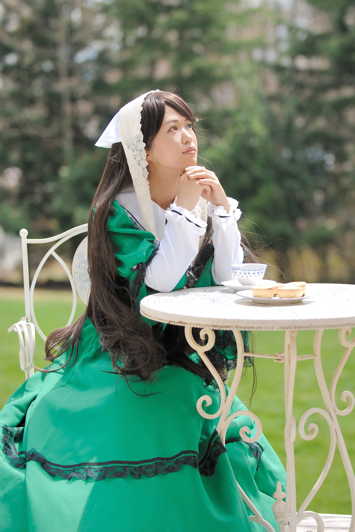 1girl blurry blurry_background brown_hair chair depth_of_field dress frills green_dress long_hair long_sleeves sitting solo suiseiseki table very_long_hair