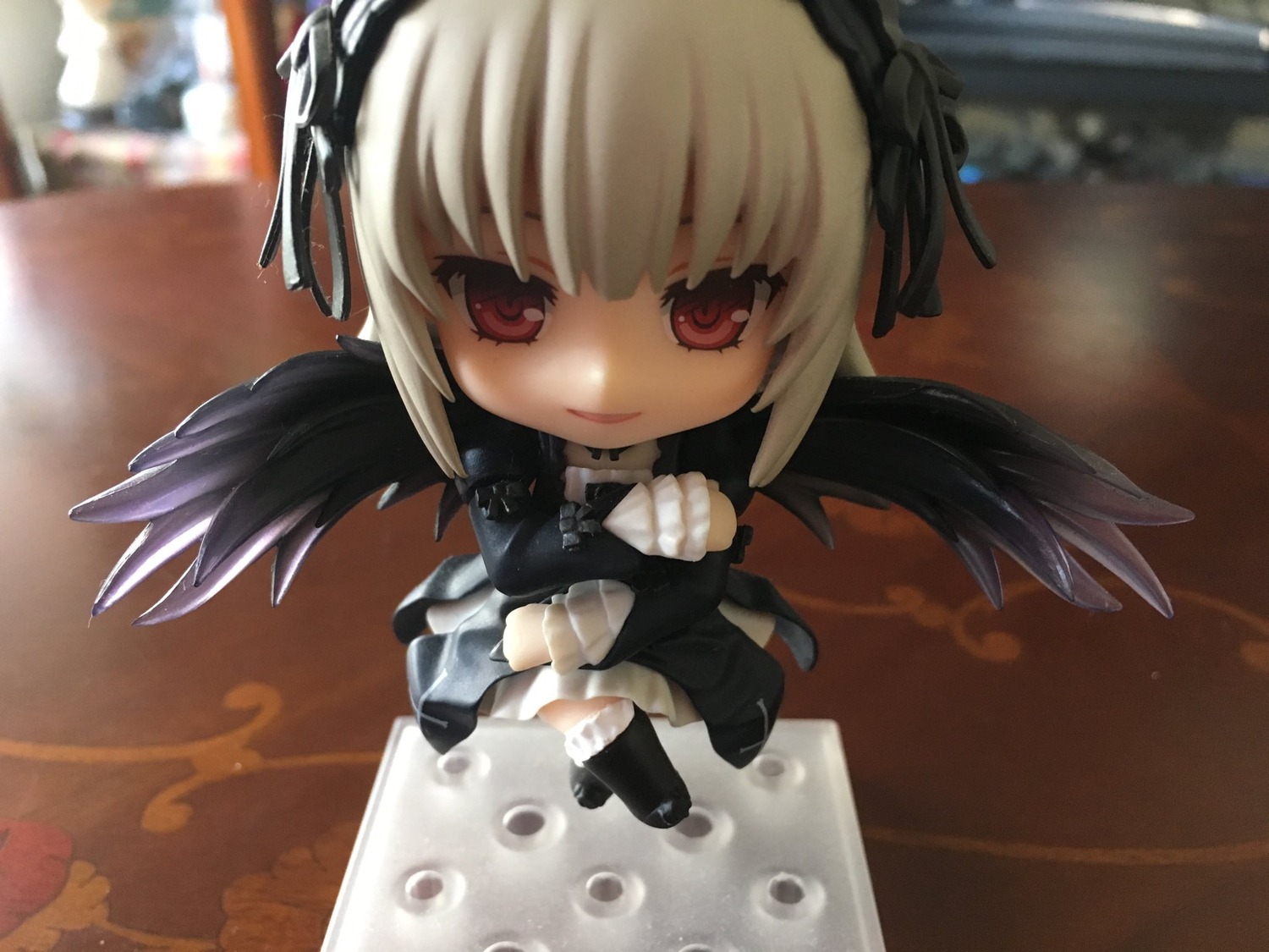 1girl 3d black_wings chibi doll dress hairband long_hair long_sleeves looking_at_viewer photo red_eyes ribbon sitting smile solo suigintou wings