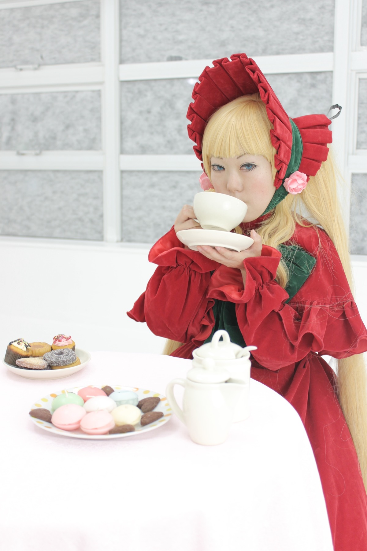 1girl bangs blonde_hair blue_eyes bonnet bow cup dress flower food frills long_hair long_sleeves red_dress saucer shinku sitting solo table tea teacup teapot tiered_tray window