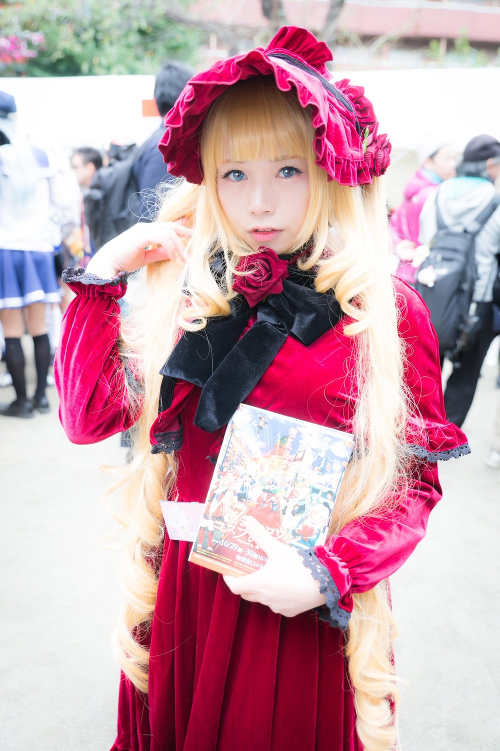 blonde_hair blue_eyes blurry blurry_background blurry_foreground book depth_of_field figure flower looking_at_viewer photo rose shinku skirt solo solo_focus