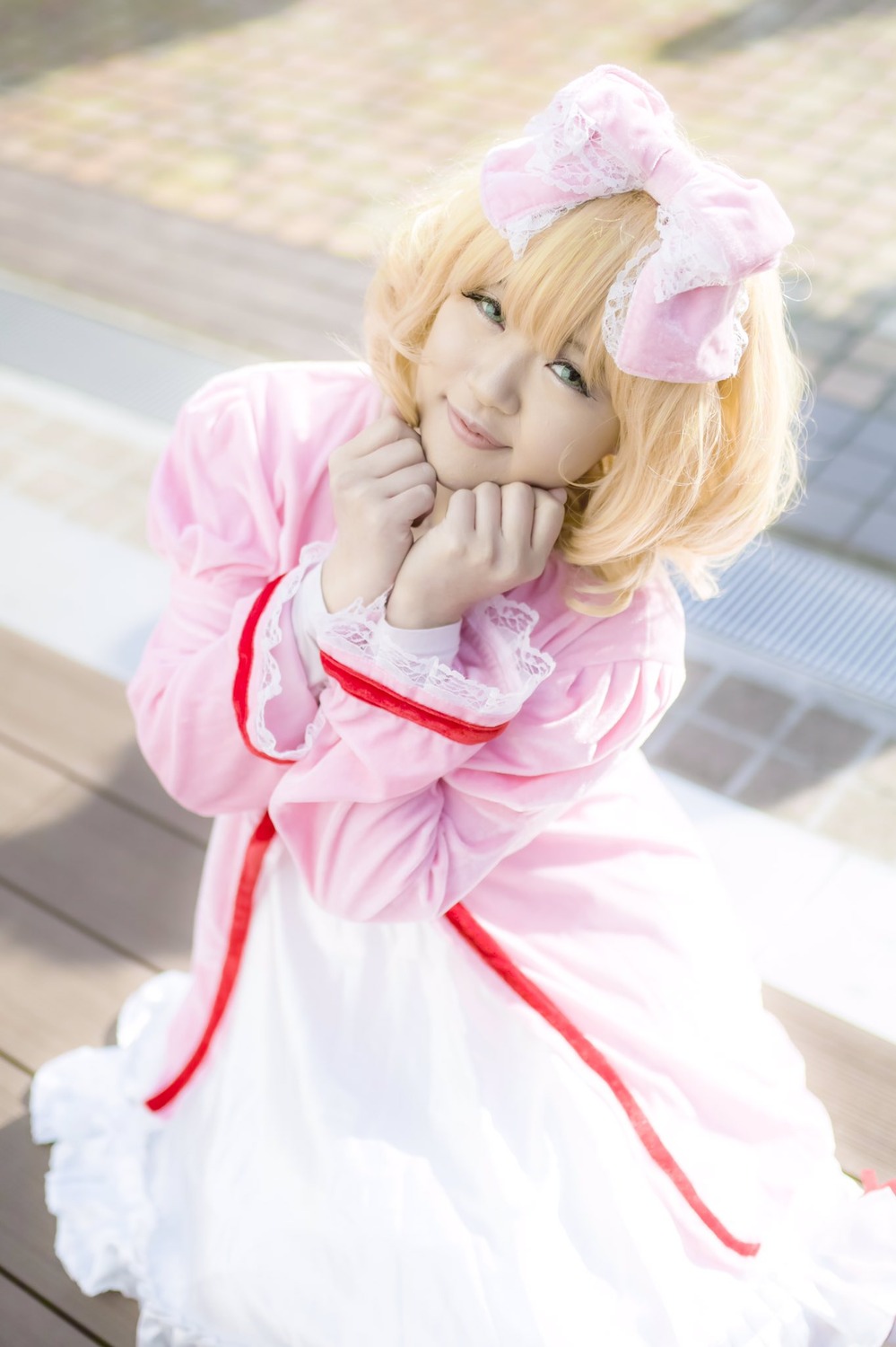 1girl blonde_hair blue_eyes blurry blurry_background bow day depth_of_field dress fence frills hinaichigo lips long_sleeves looking_at_viewer outdoors pink_dress ribbon short_hair smile solo