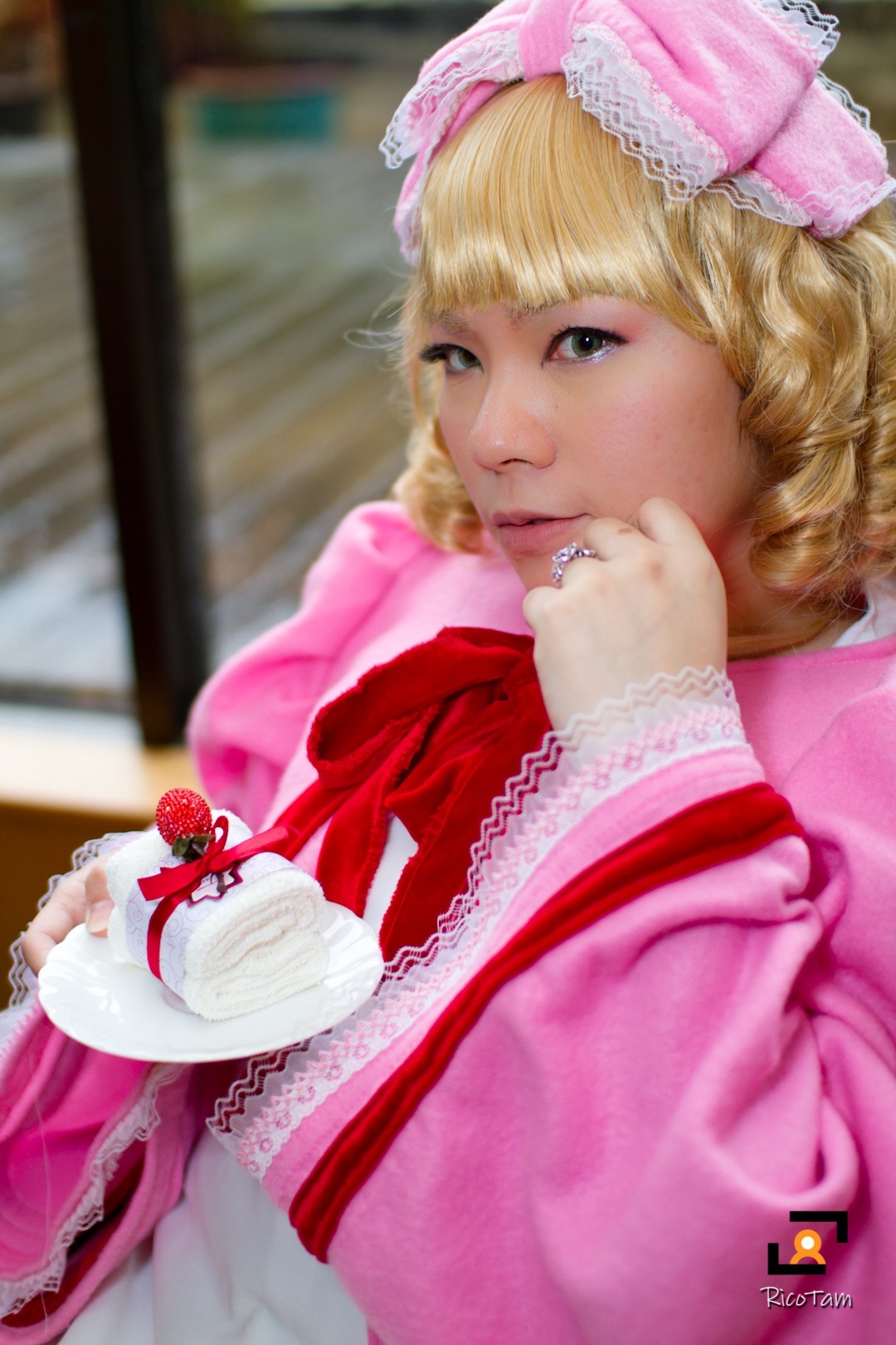 1girl bangs blonde_hair blurry blurry_background blurry_foreground bow cake depth_of_field dress drill_hair food frills fruit hinaichigo pink_bow pink_dress plate realistic ribbon solo strawberry table