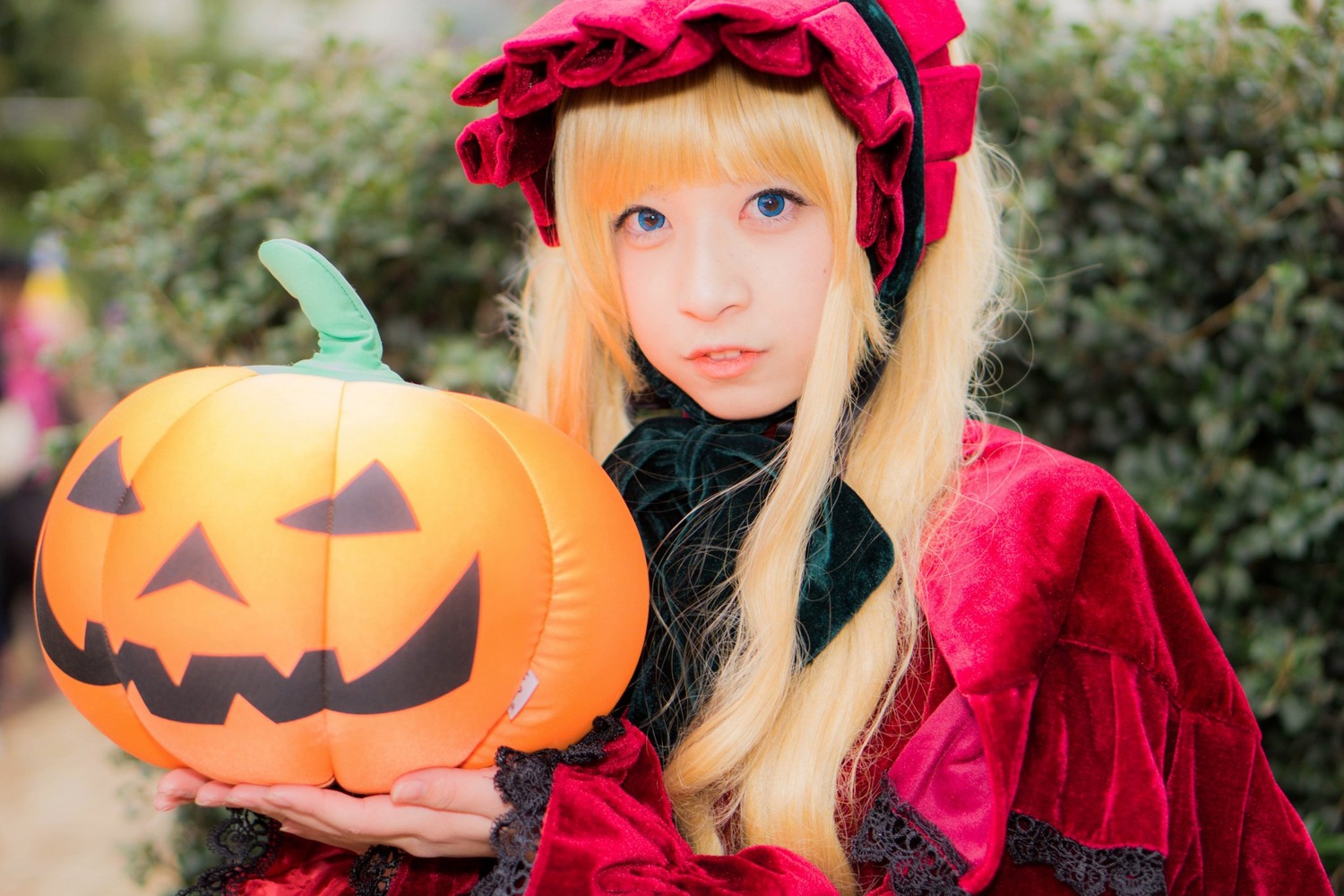 1girl bangs blonde_hair blue_eyes blurry blurry_background bonnet closed_mouth depth_of_field halloween hat jack-o'-lantern lips long_hair long_sleeves looking_at_viewer outdoors pumpkin solo upper_body