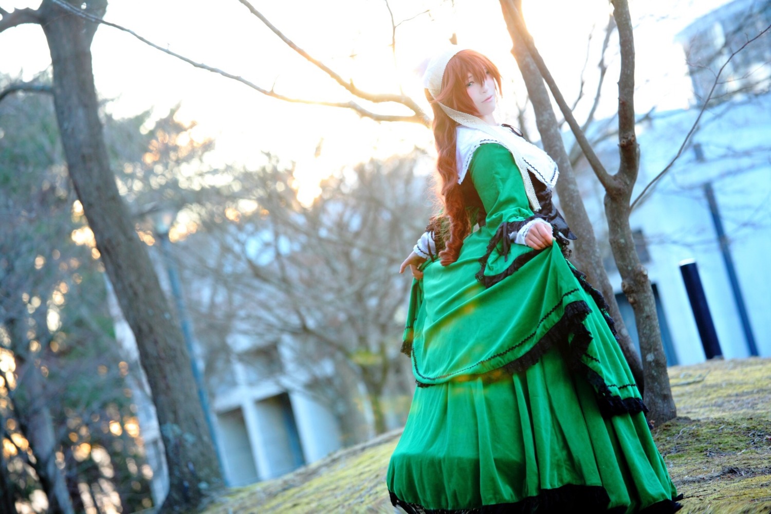 1girl blurry brown_hair depth_of_field dress green_dress long_hair long_sleeves outdoors pointy_ears skirt_hold solo suiseiseki tree