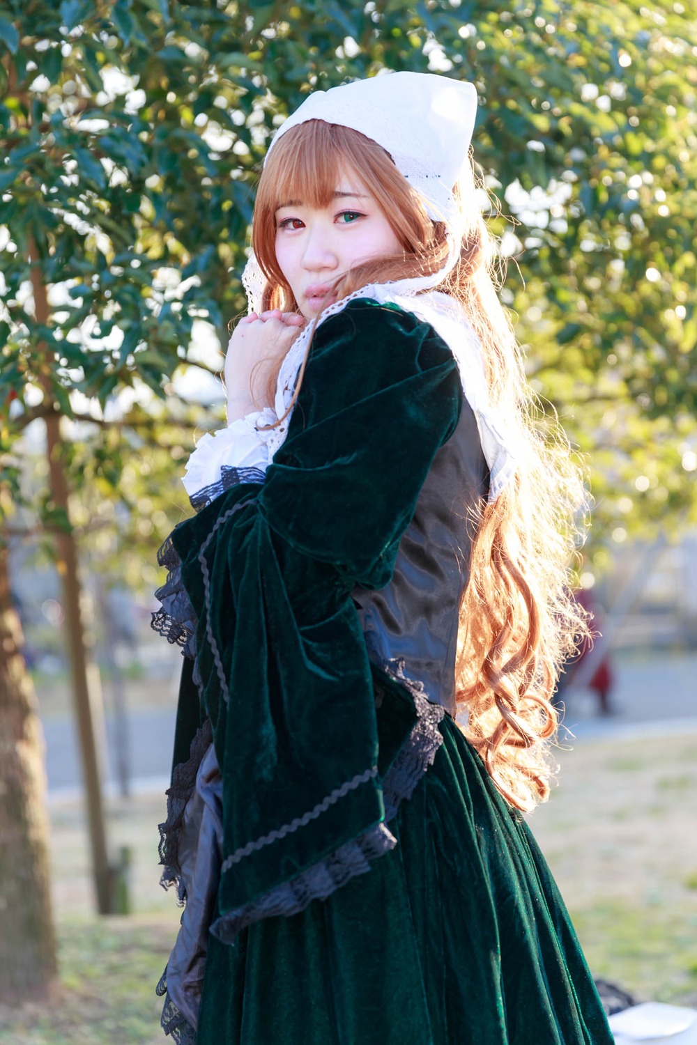 1girl black_dress blurry blurry_background blurry_foreground brown_hair depth_of_field dress green_eyes heterochromia long_hair looking_at_viewer nun outdoors red_eyes solo suiseiseki