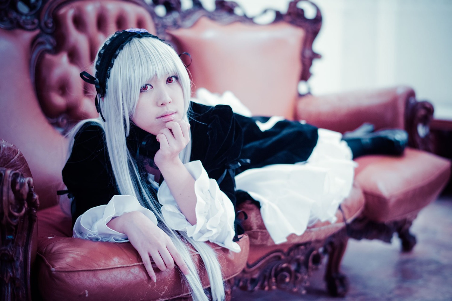 1girl blurry blurry_background blurry_foreground chair depth_of_field dress frilled_sleeves frills gothic_lolita hairband lolita_fashion long_hair long_sleeves looking_at_viewer red_eyes sitting solo suigintou white_hair