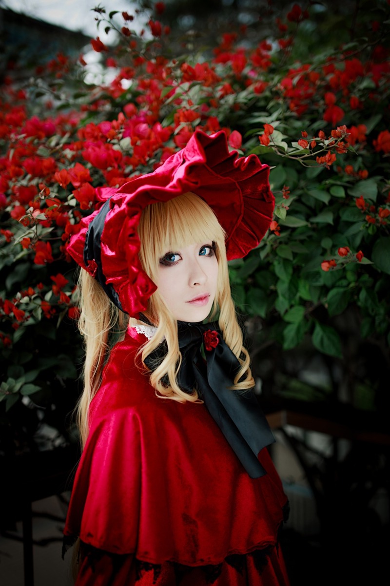 1girl bangs blonde_hair blue_eyes blurry bonnet capelet depth_of_field dress flower lips long_hair looking_at_viewer red_capelet red_dress red_flower red_rose rose shinku solo upper_body