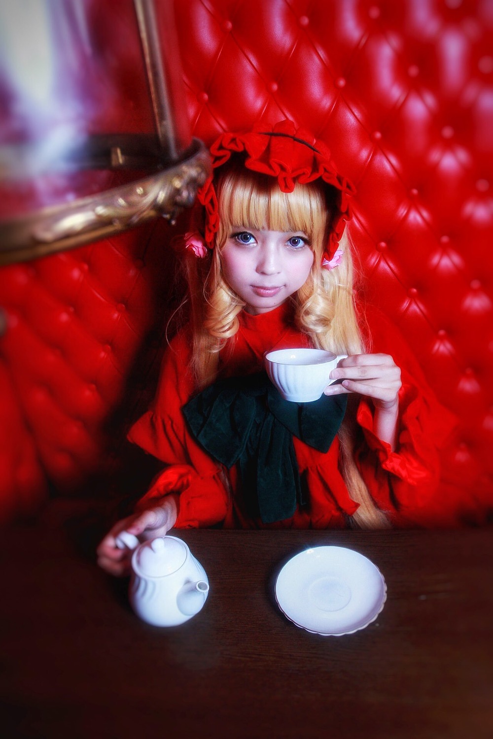 1girl bangs blonde_hair blue_eyes blurry bow cup depth_of_field dress drill_hair flower long_hair looking_at_viewer plate saucer shinku sitting smile solo table tea teacup teapot