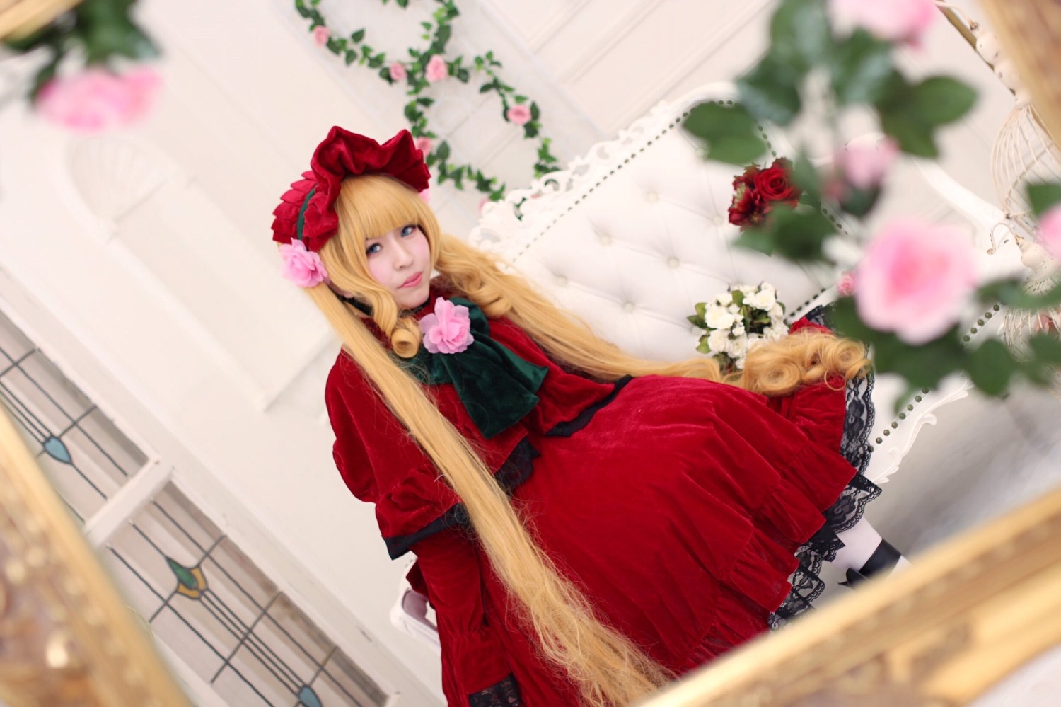 1girl blonde_hair blue_eyes blurry blurry_background blurry_foreground bow depth_of_field dress flower lips long_hair motion_blur photo red_dress shinku sitting solo