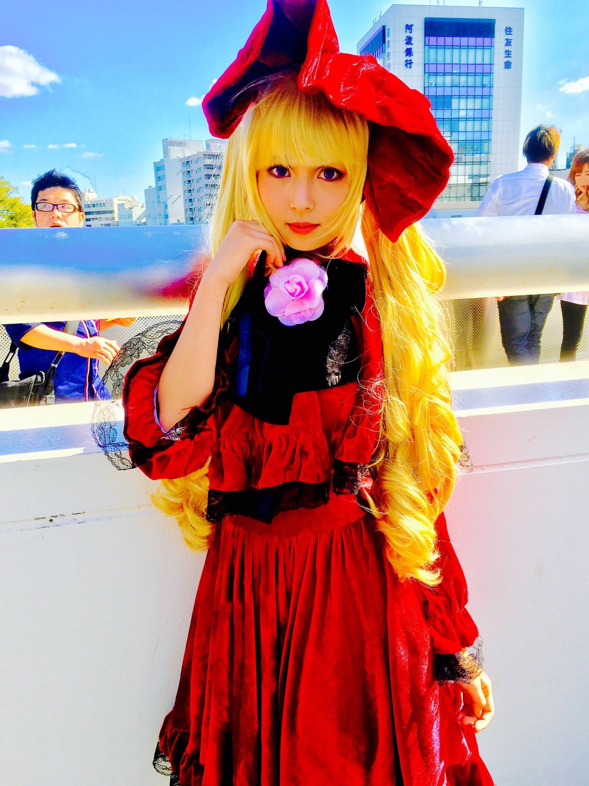 1girl blonde_hair bow building city day dress drill_hair flower long_hair looking_at_viewer outdoors photo red_dress rose shinku sky smile solo