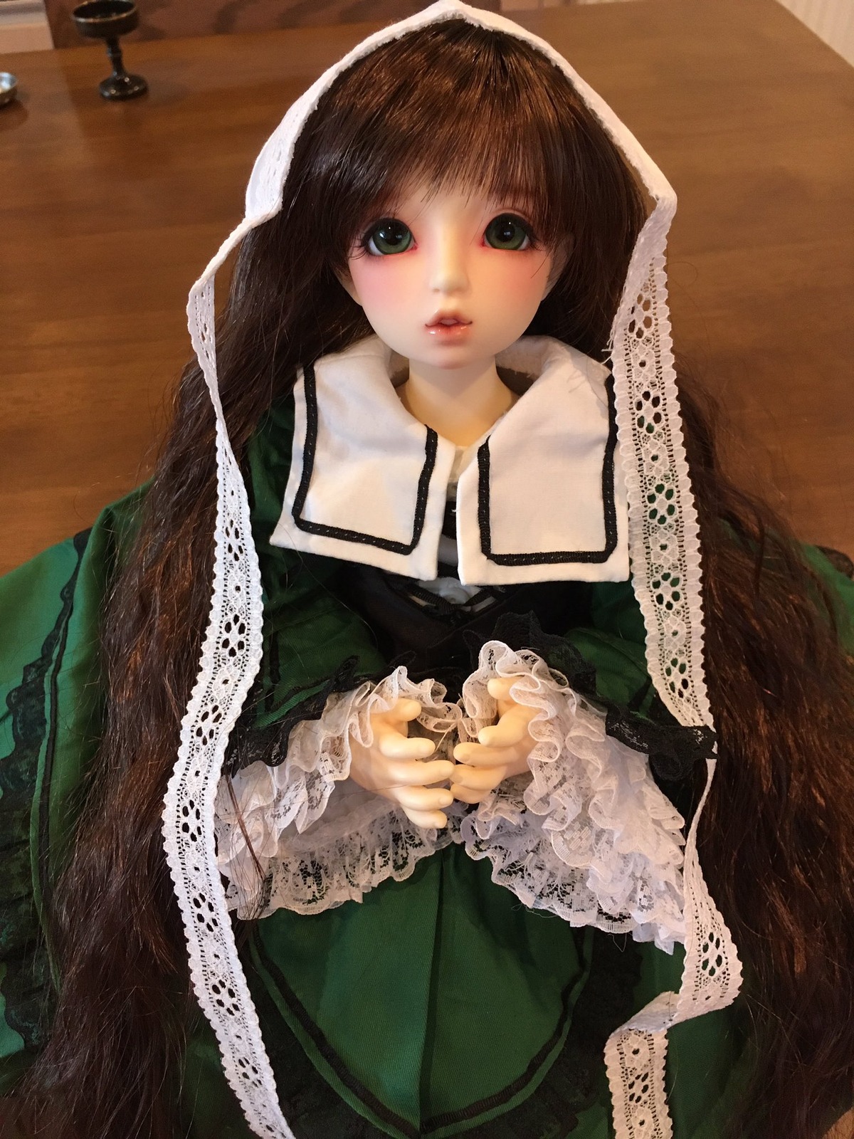 1girl bangs brown_hair doll dress frills green_dress lace lips long_hair long_sleeves looking_at_viewer own_hands_together photo solo suiseiseki