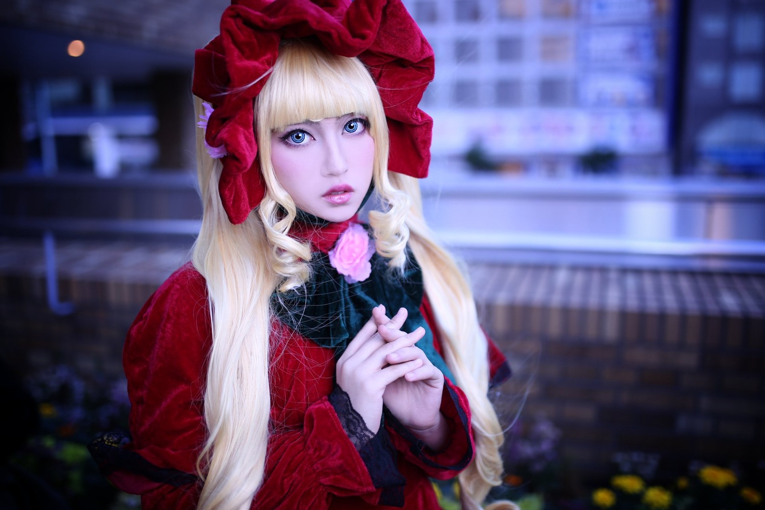 1girl bangs blonde_hair blue_eyes blurry blurry_background bonnet building city depth_of_field dress flower hands_together lips long_hair long_sleeves looking_at_viewer outdoors own_hands_together shinku solo upper_body