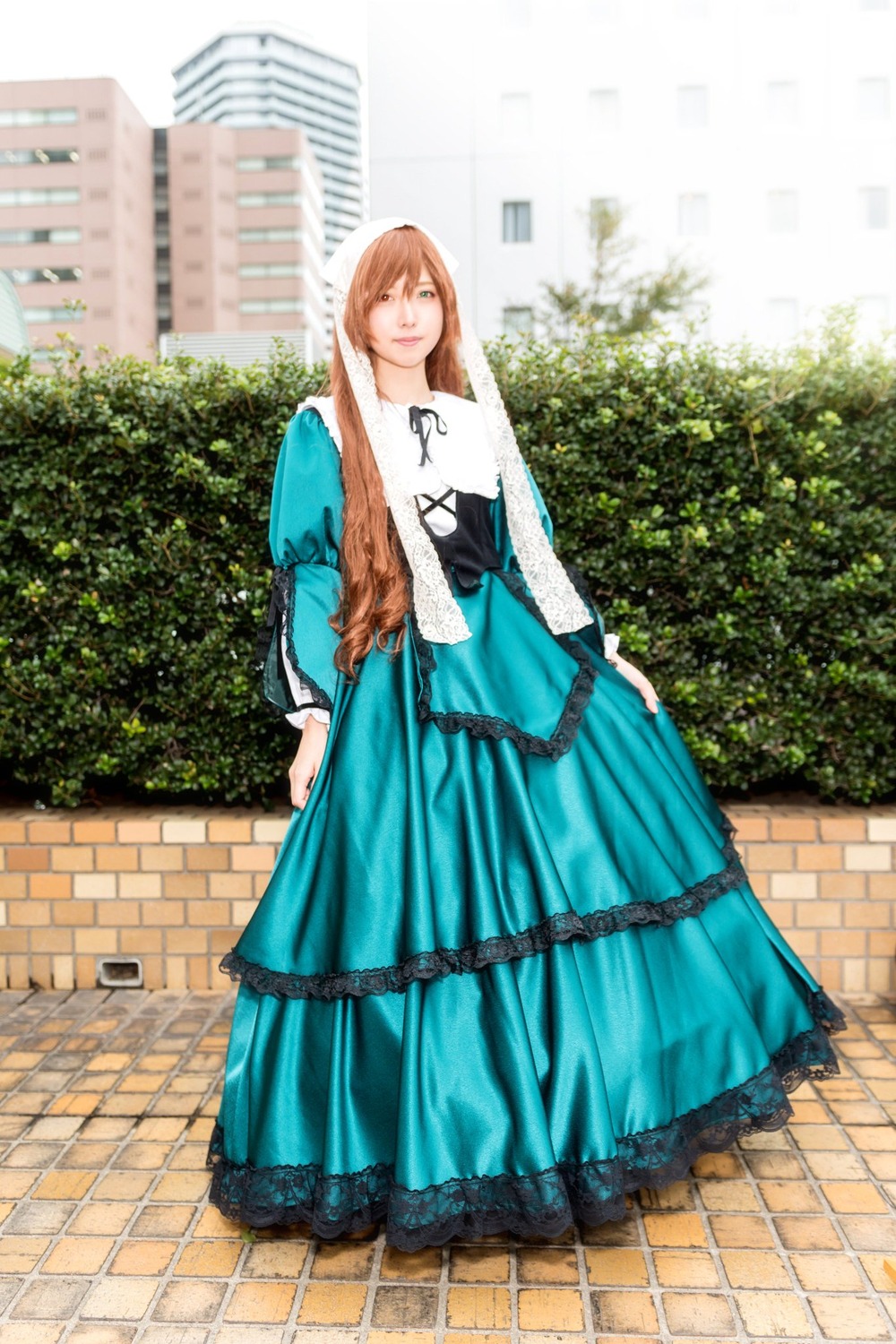 1girl blonde_hair blue_dress brown_hair building day dress fence full_body long_hair long_sleeves one_eye_closed outdoors pavement smile solo standing suiseiseki