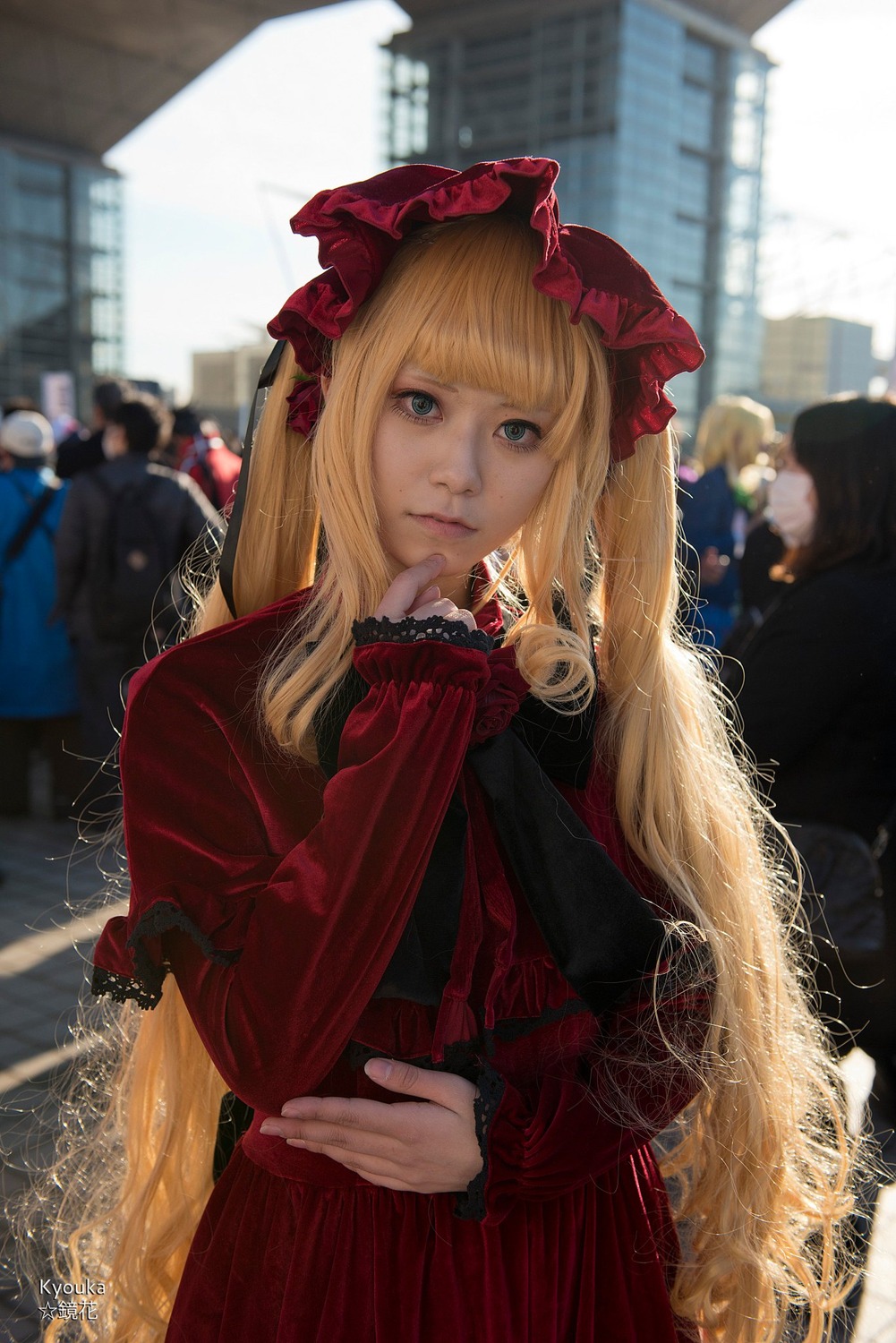 1girl 6+boys bangs blonde_hair blurry blurry_background building city crowd depth_of_field dress long_hair long_sleeves looking_at_viewer multiple_boys outdoors realistic red_dress shinku solo solo_focus very_long_hair