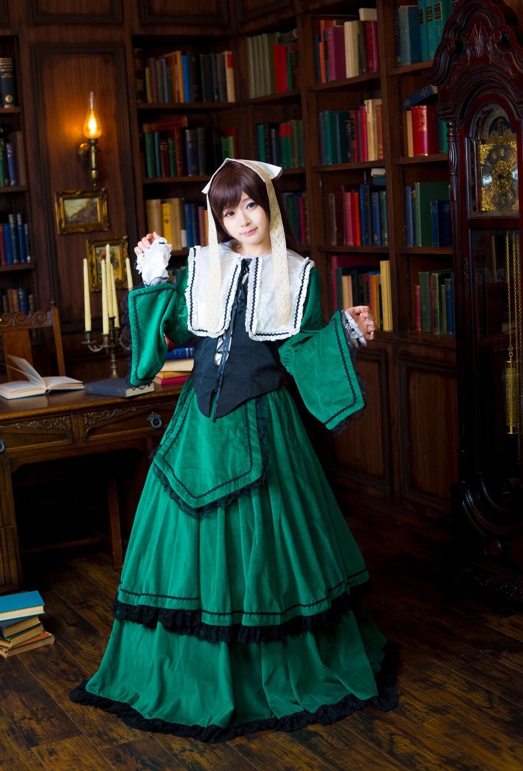 1girl blue_eyes book book_stack bookshelf brown_hair green_dress indoors long_skirt looking_at_viewer open_book solo standing suiseiseki