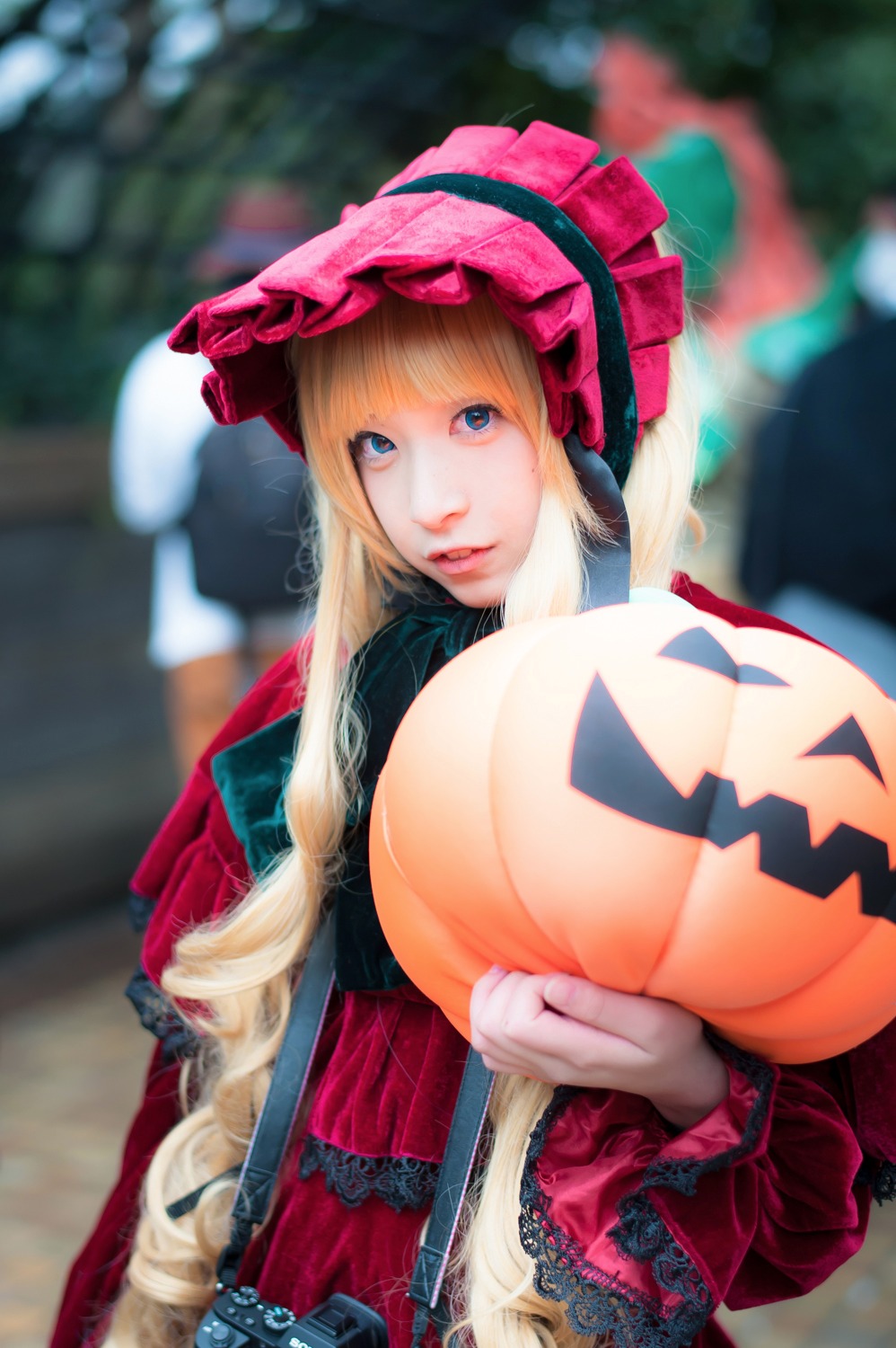 1girl ball bangs blonde_hair blue_eyes blurry blurry_background blurry_foreground bonnet depth_of_field dress flower hat jack-o'-lantern lips long_sleeves looking_at_viewer outdoors photo shinku solo upper_body