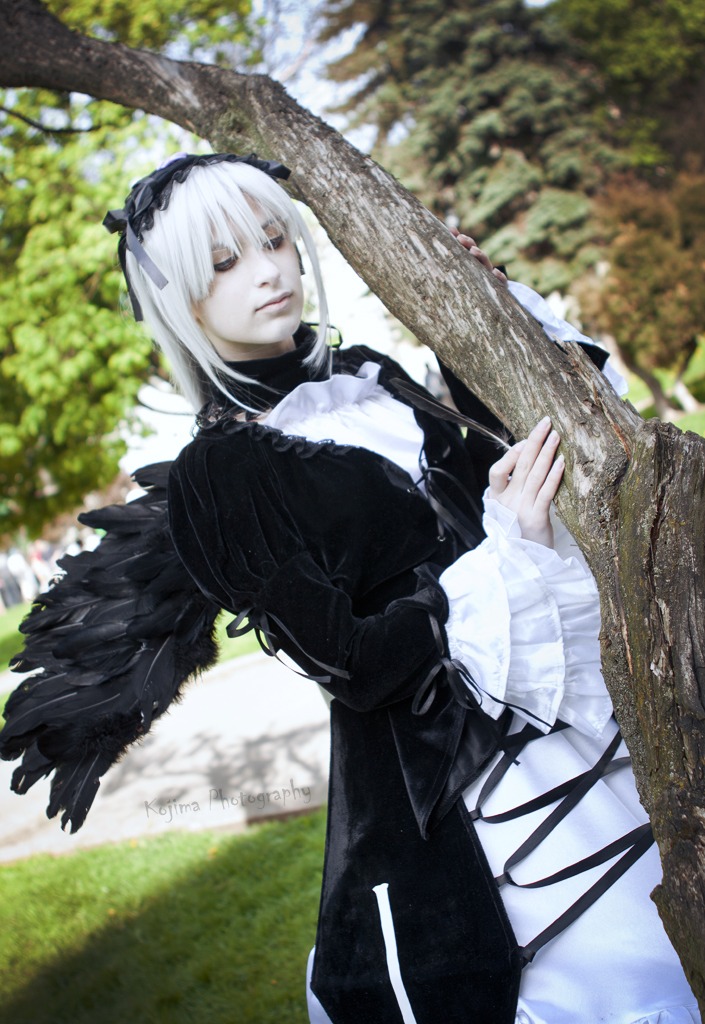 1girl black_dress black_wings blurry blurry_background day depth_of_field dress feathered_wings frills hairband lips long_sleeves outdoors photo short_hair solo suigintou tree wings