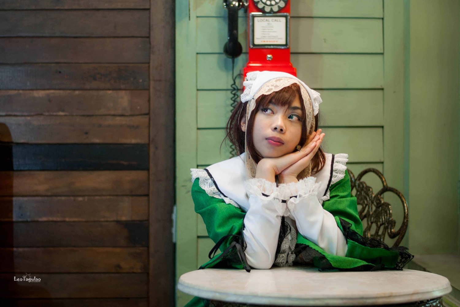 1girl artist_name brown_hair dress green_dress hat indoors lips looking_at_viewer realistic signature sitting solo suiseiseki table