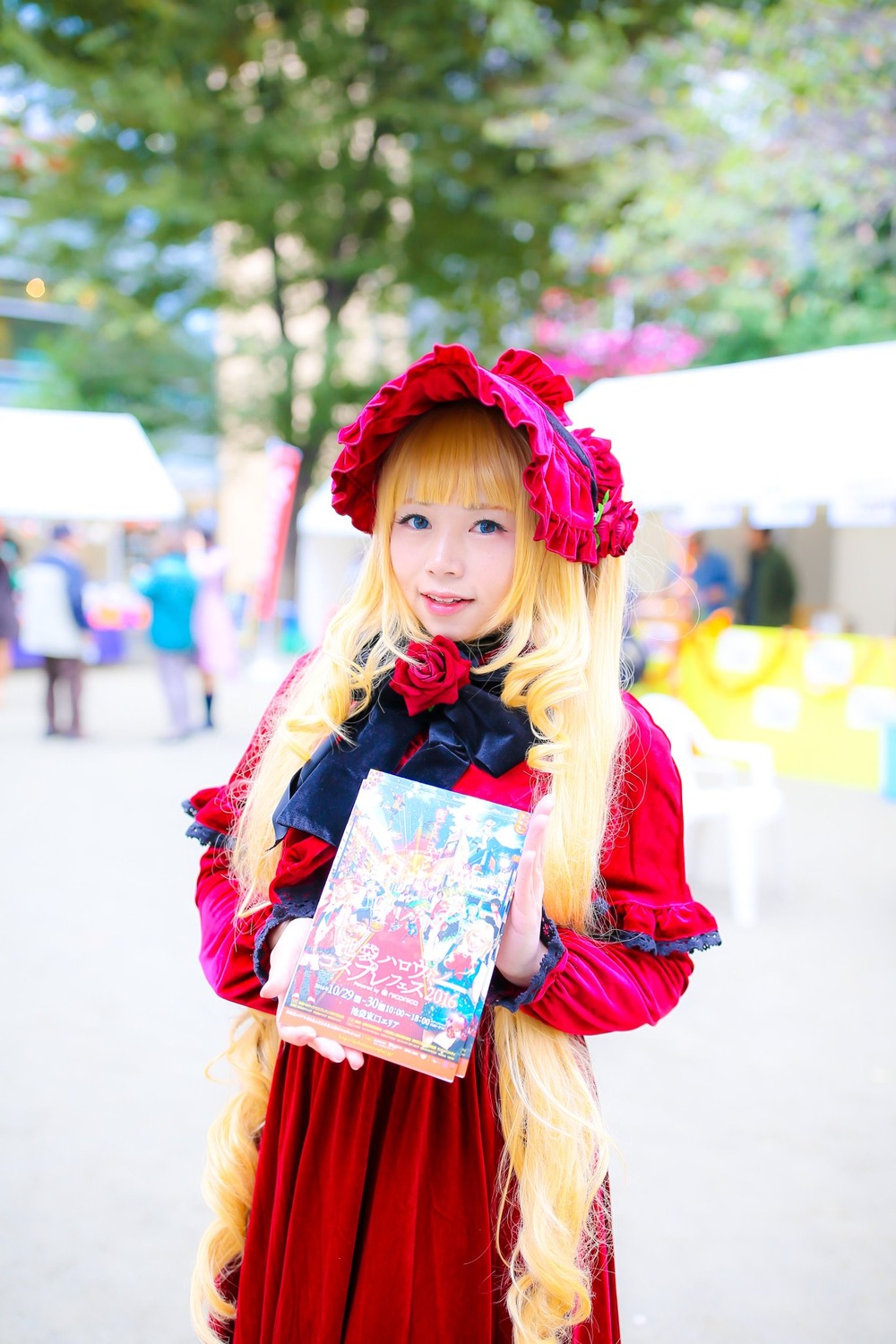 1girl bangs blonde_hair blue_eyes blurry blurry_background blurry_foreground depth_of_field dress flower lips long_hair looking_at_viewer photo red_dress red_flower red_rose rose shinku solo