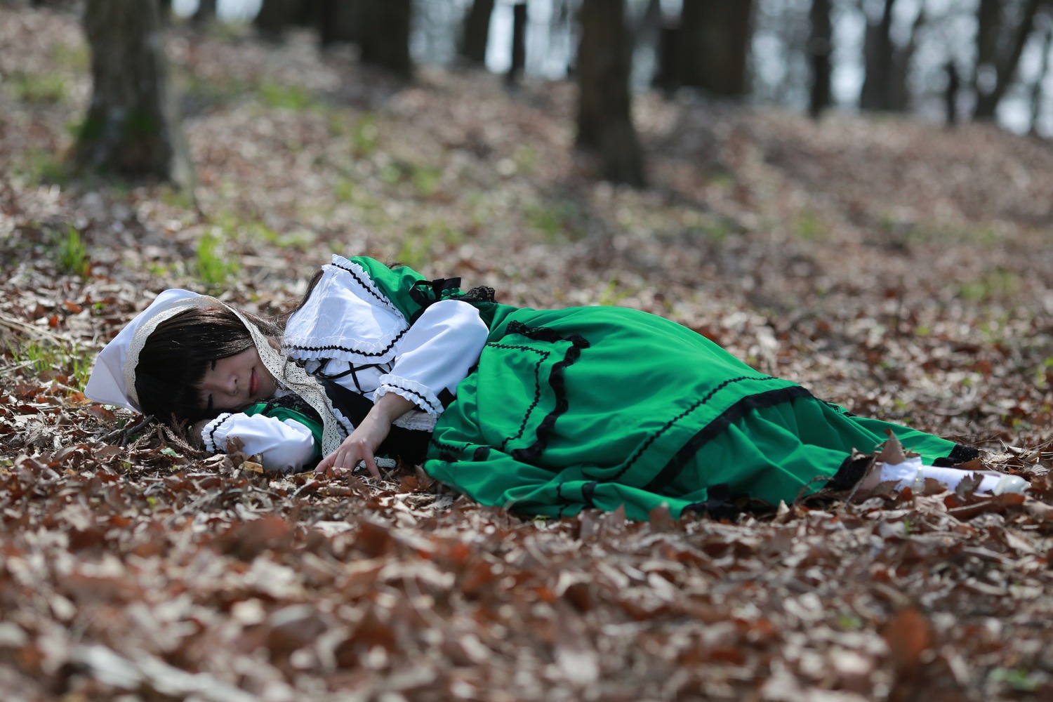 1girl black_hair blurry blurry_background blurry_foreground closed_eyes depth_of_field dress frills green_dress long_sleeves lying motion_blur on_side photo photo_background solo suiseiseki