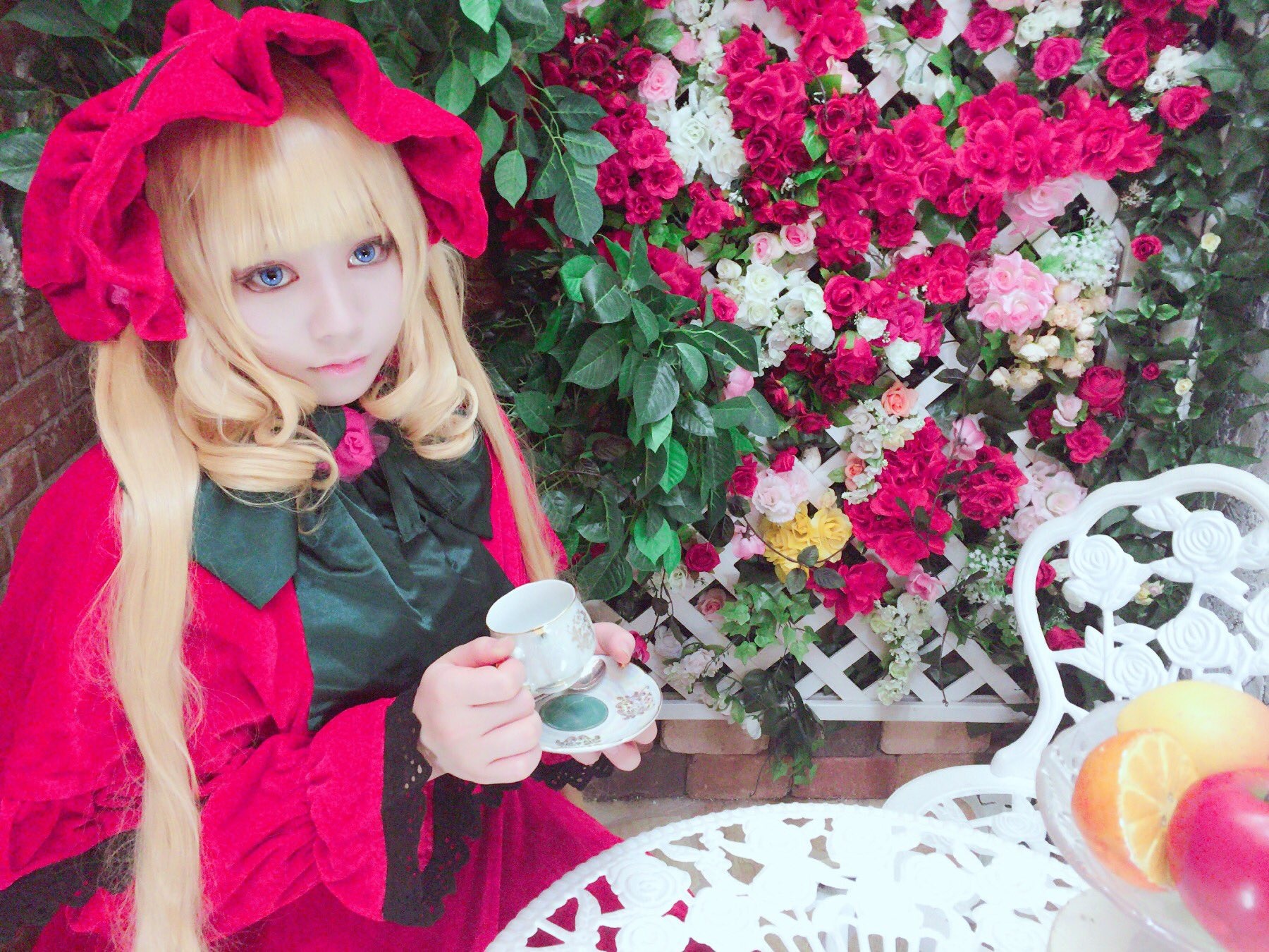 1girl bangs blonde_hair blue_eyes bow cup dress flower hat long_hair looking_at_viewer pink_flower pink_rose red_flower red_rose rose shinku sitting solo teacup traditional_media