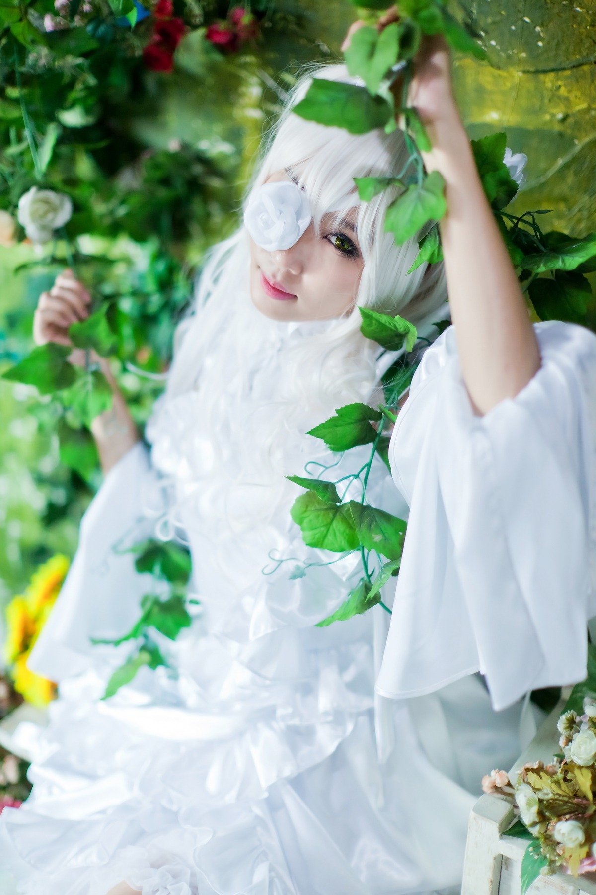 1girl bangs blurry blurry_background blurry_foreground closed_mouth day depth_of_field dress flower green_eyes kirakishou leaf lips looking_at_viewer one_eye_covered plant smile solo white_dress white_hair