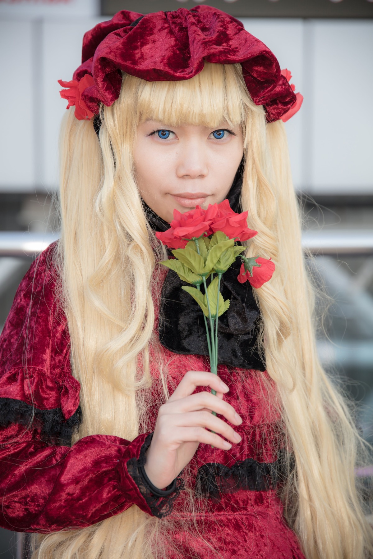 1girl bangs blonde_hair blue_eyes blurry dress flower holding holding_flower lips long_hair long_sleeves looking_at_viewer red_dress red_flower rose shinku solo upper_body