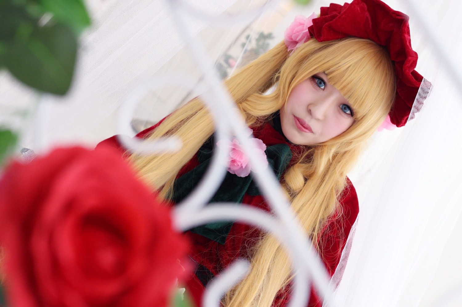 1girl bangs blonde_hair blue_eyes blurry blurry_background blurry_foreground depth_of_field dress flower lips long_hair looking_at_viewer motion_blur photo red_dress red_flower red_rose rose shinku solo
