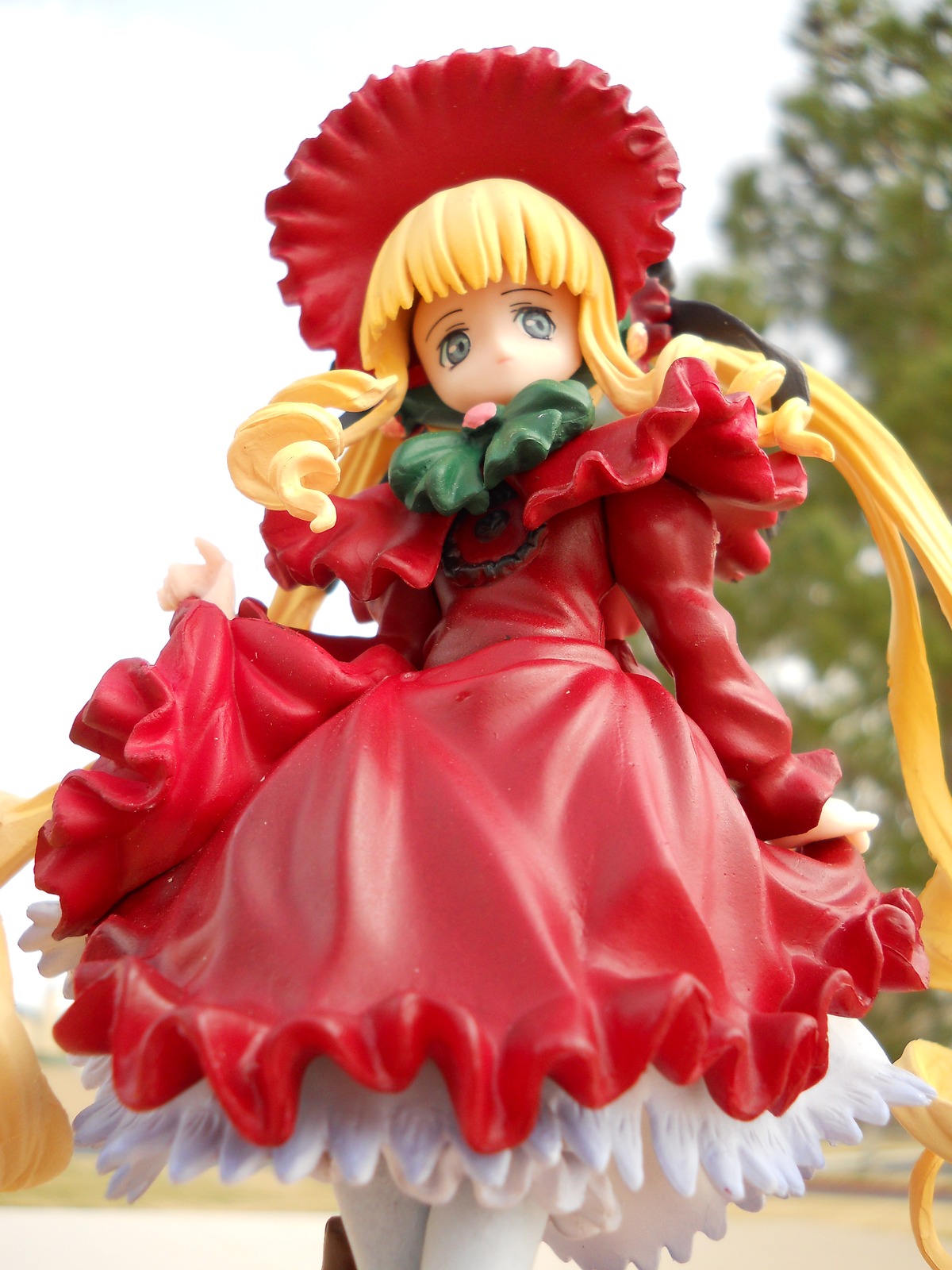 1girl bangs blonde_hair blue_eyes blurry bonnet bow depth_of_field doll dress frills long_hair long_sleeves looking_at_viewer pantyhose red_dress shinku solo standing twintails